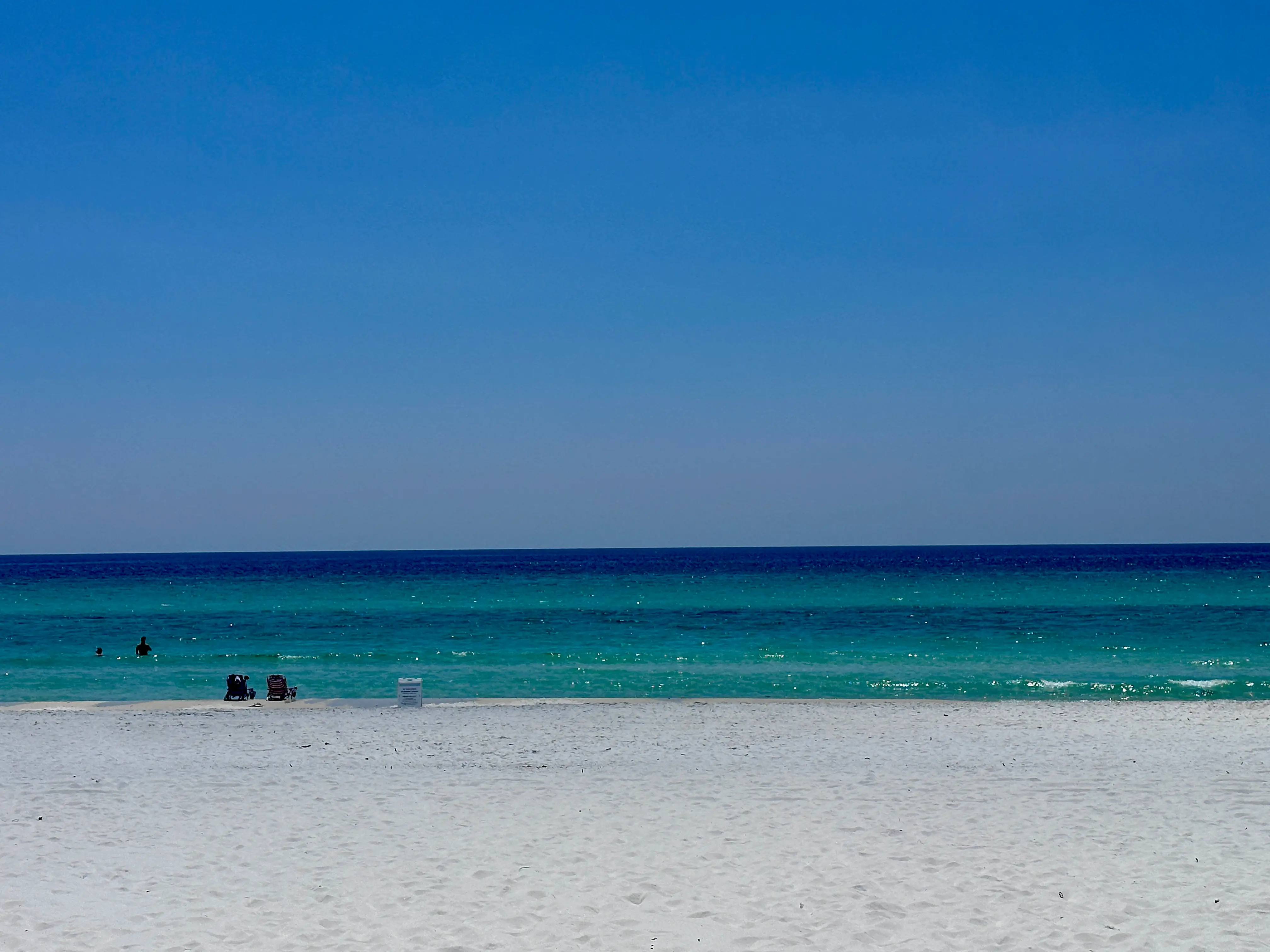 A beach with white sand and turquoise water.