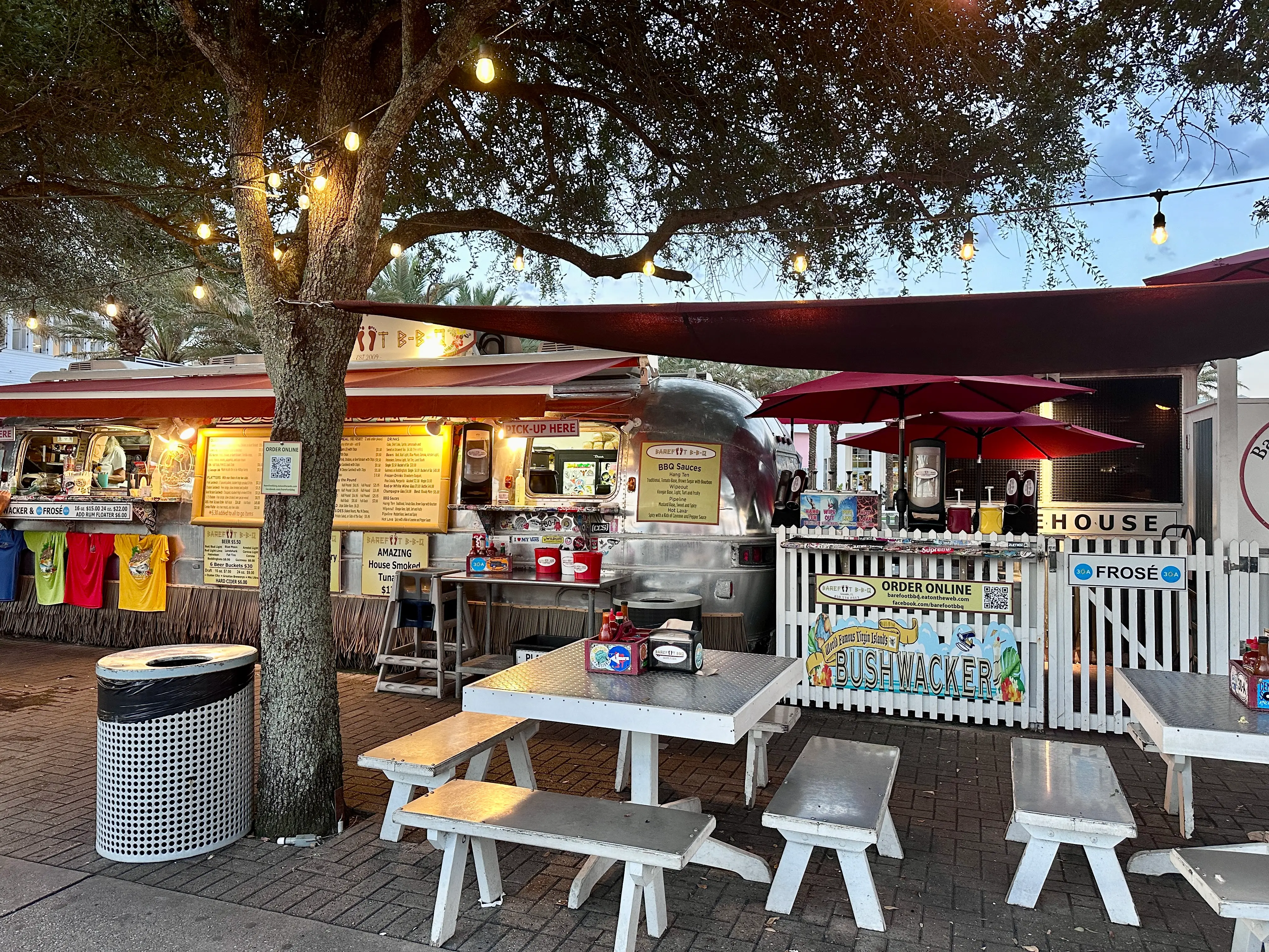 Seating area and airstream food trucks under a tree at Airstream Row in Seaside