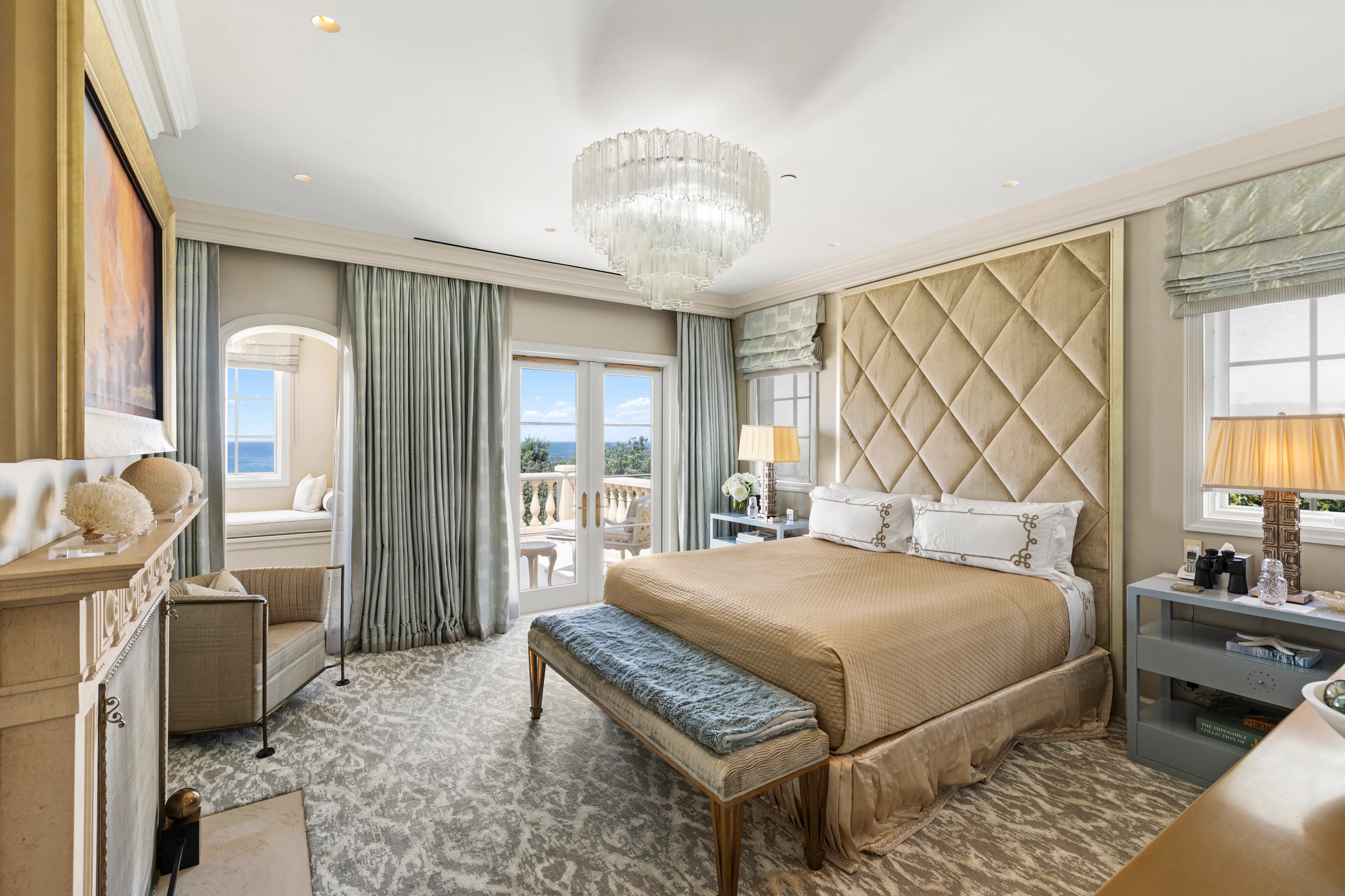 A bedroom in the Sand Castle mansion with a crystal chandelier and balcony.