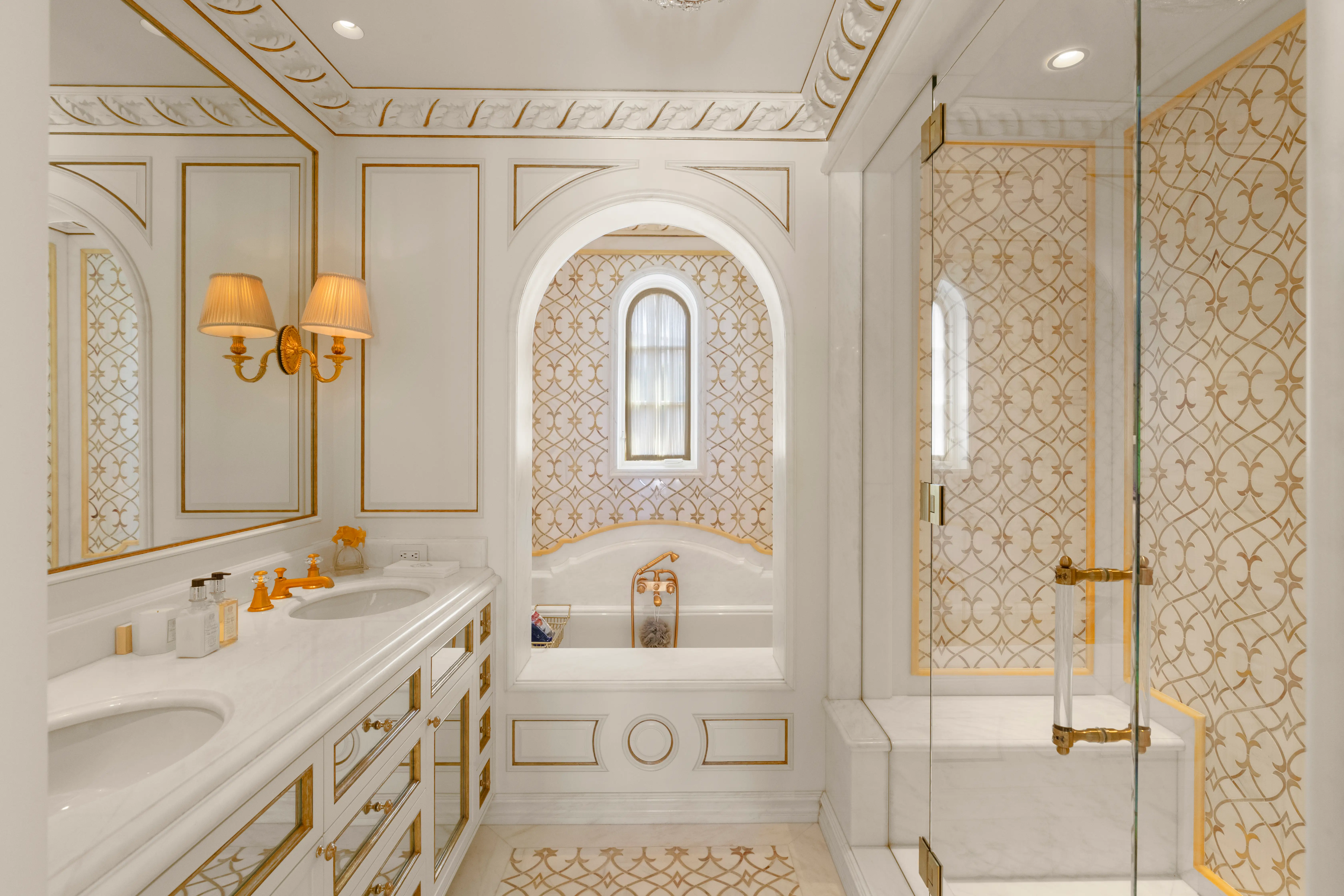 A bathroom in the Sand Castle mansion, featuring white marble and gold-design tiles.