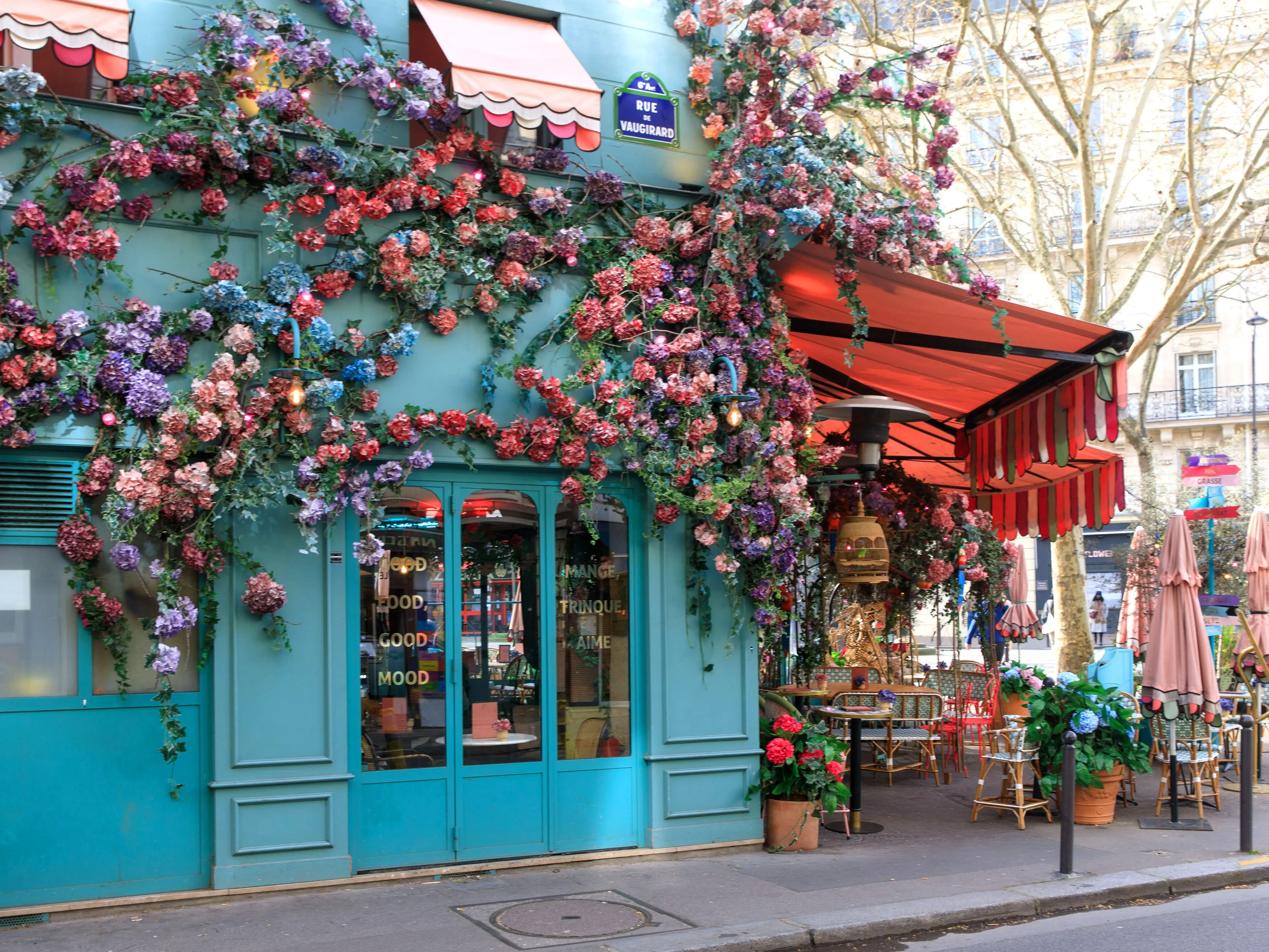 Colorful flowers on a turquoise restaurant building in Paris.