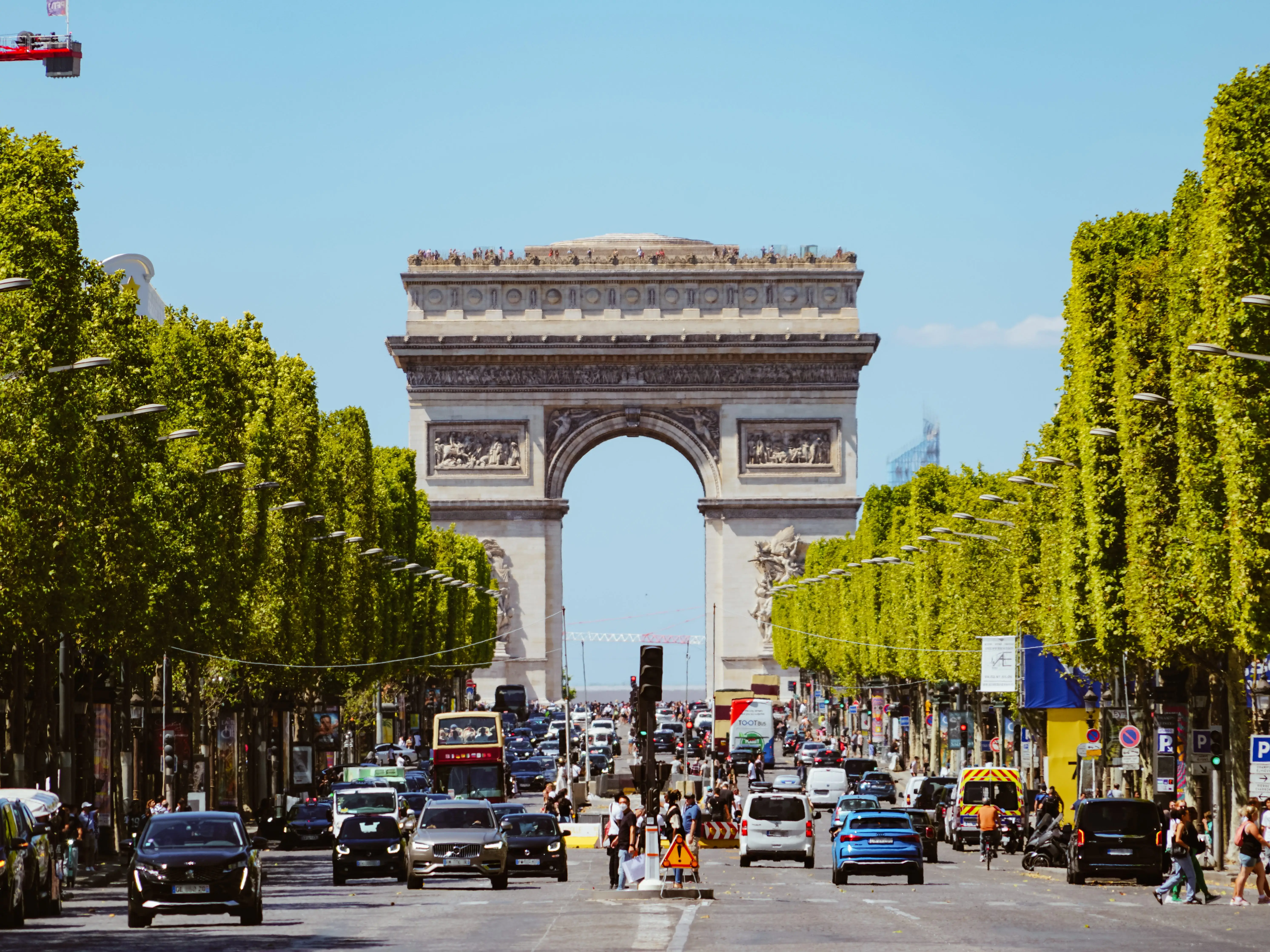 Rows of trees line a busy street at the Arc de Triomphe.