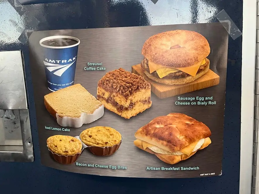 An Amtrak food menu with images of hot coffee, a streusel coffee cake, sausage, egg, and cheese on a bialy roll, an artisan breakfast sandwich, an iced lemon cake, and bacon-and-cheese egg bites.