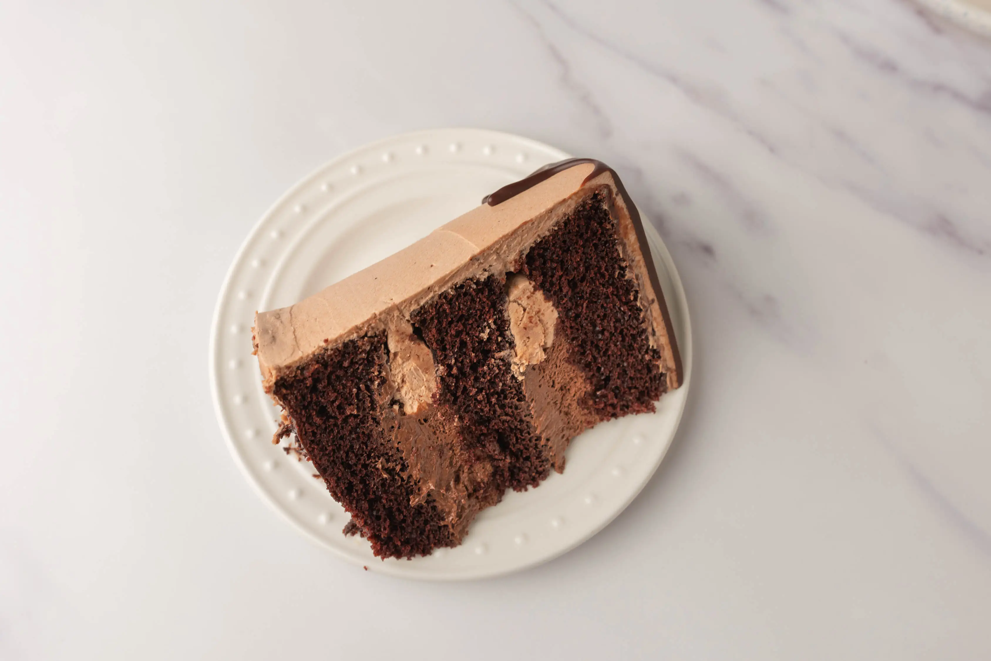 Slice of chocolate cake with lighter chocolate frosting between layers of cake