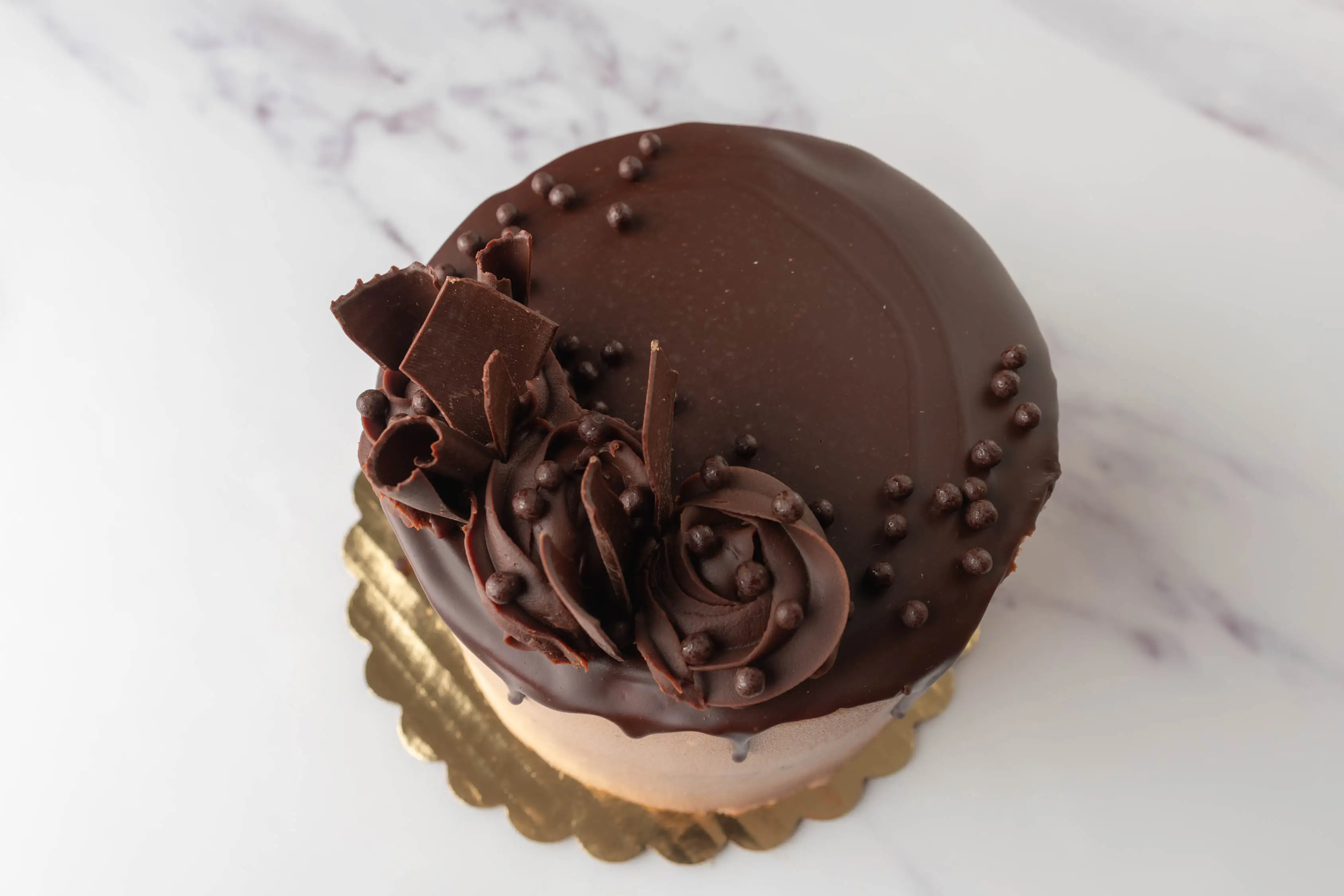 Round chocolate cake topped with chocolate pieces and chocolate swirls from WholeFoods