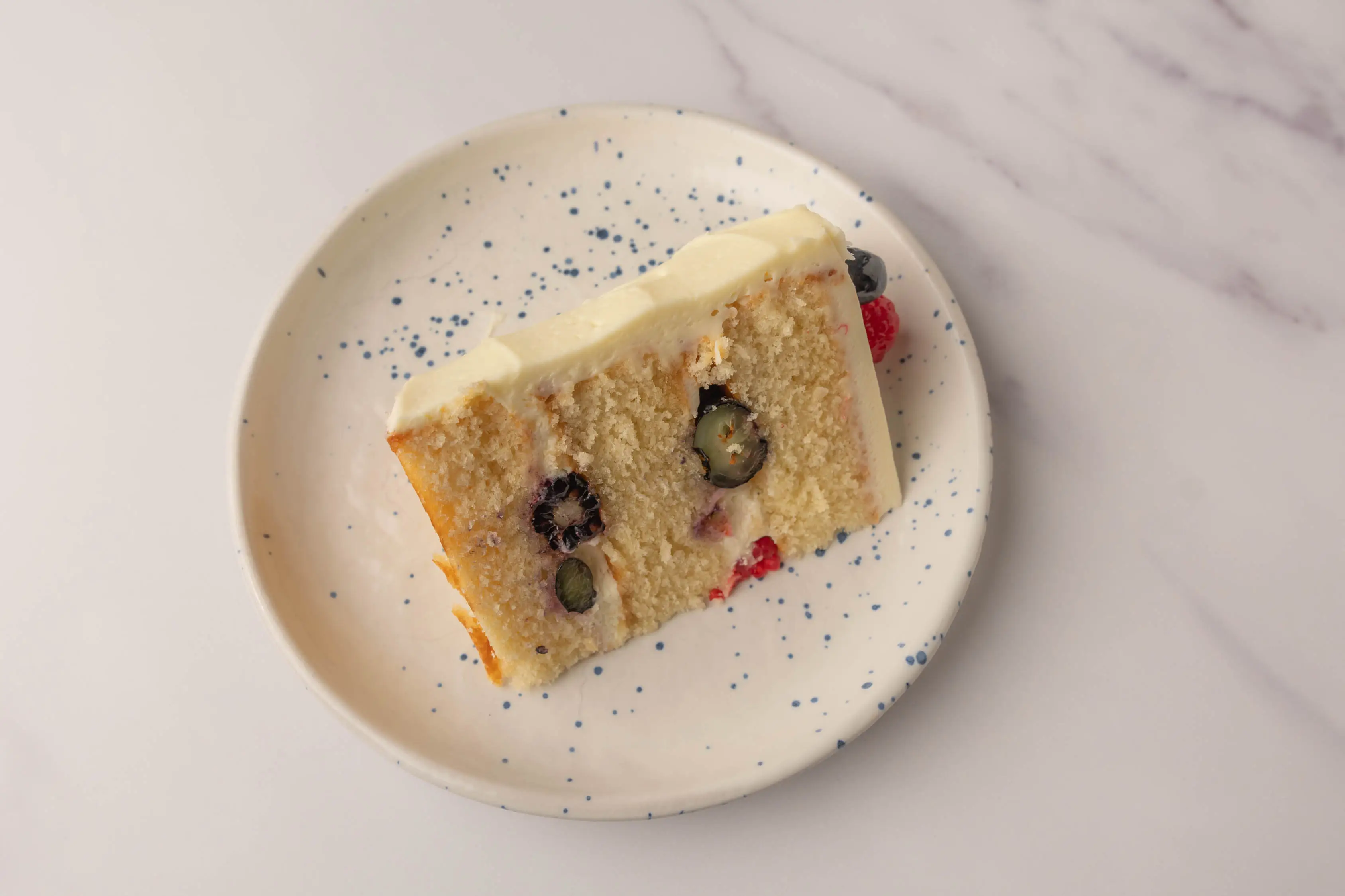 A slice of Chantilly cake with cream and berries inside.