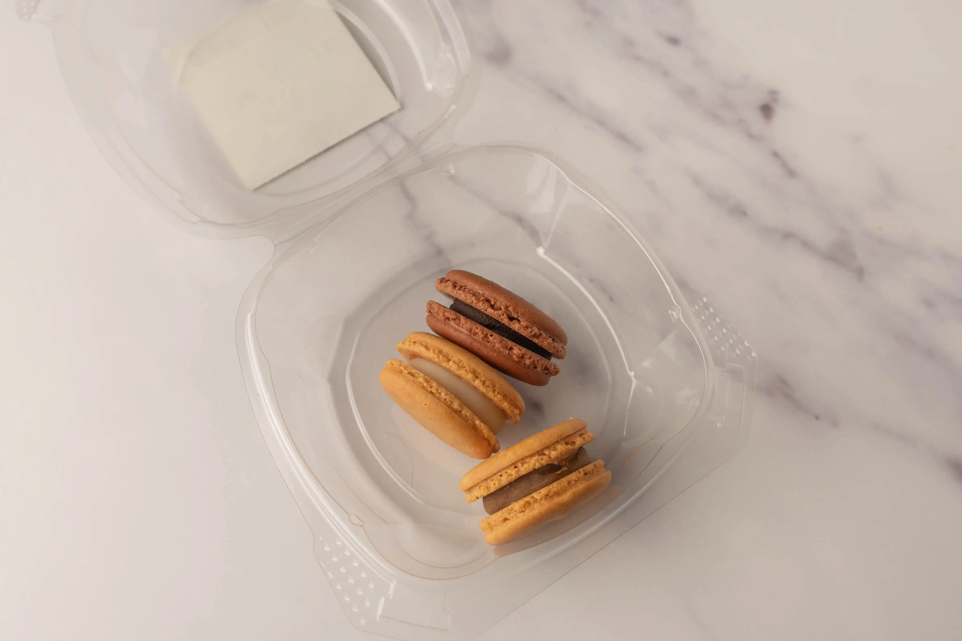 Three orange-y macarons in plastic clamshell package from Wholefoods