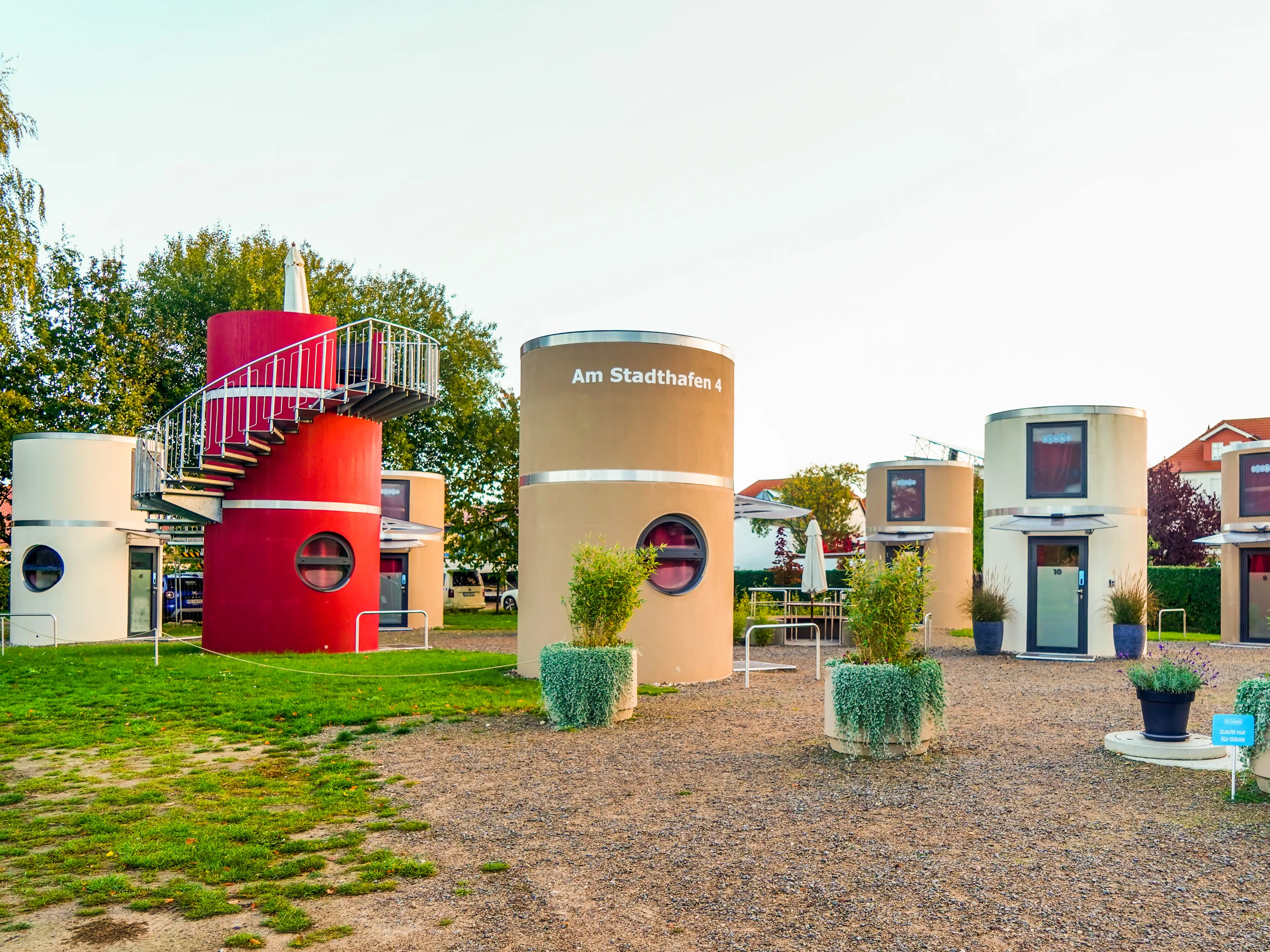 Several cylindrical homes on a flat property with grass on the left and gravel on the right