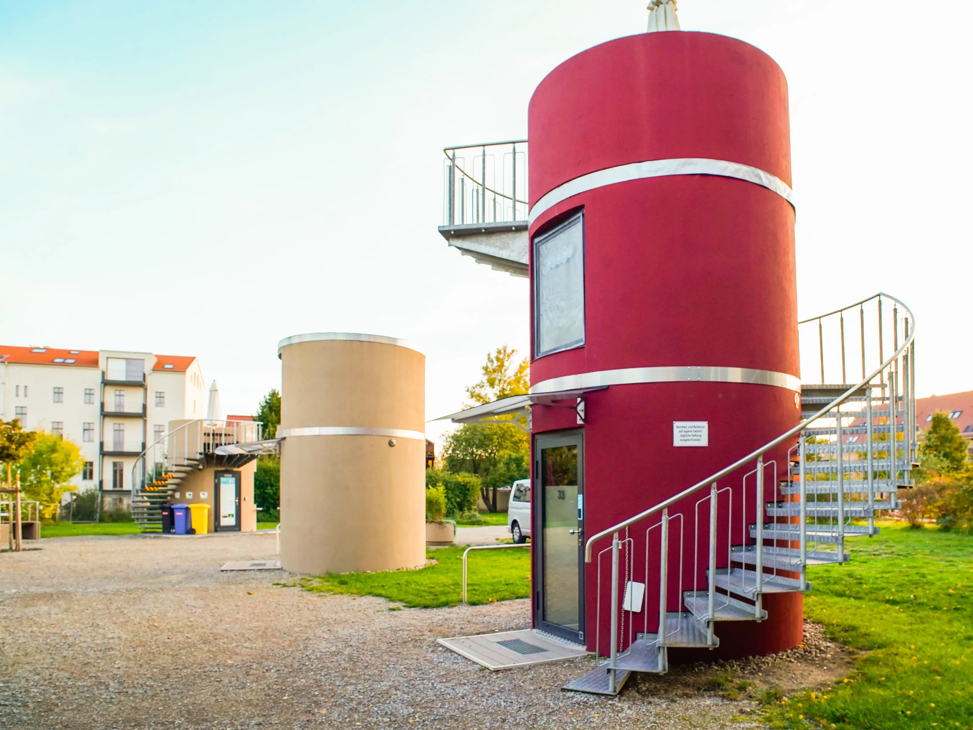 Cylindrical homes on a flat property with buildings in the background