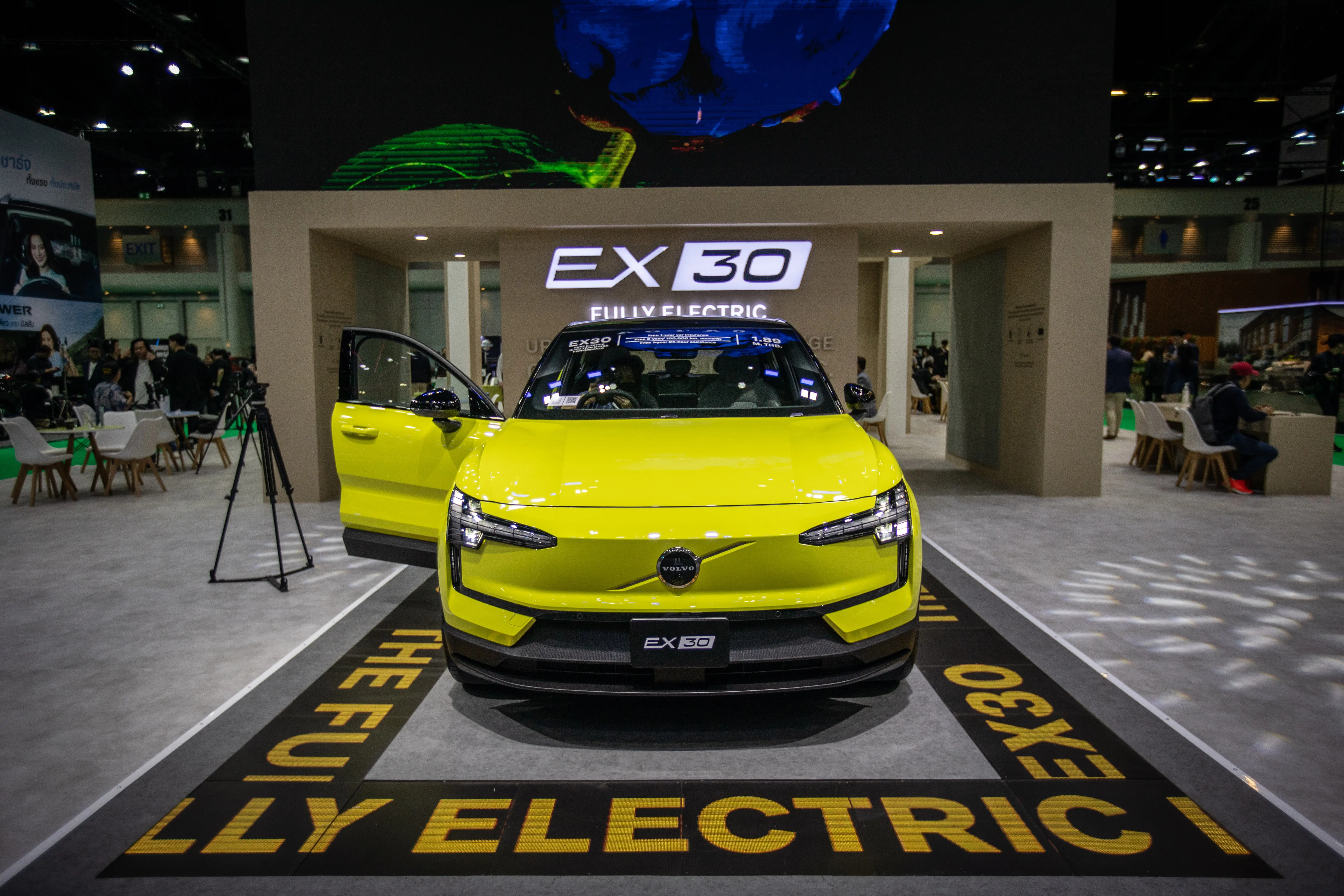 A yellow Volvo EX30 is on display during a car show.
