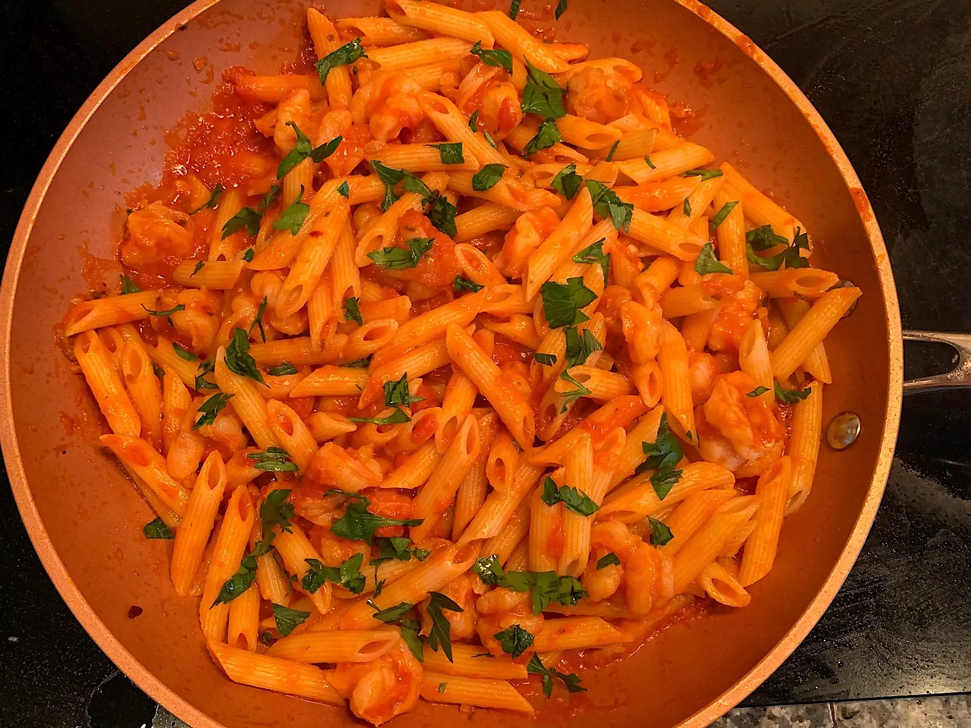 The shrimp, pasta, and sauce all mixed together, with parsley on top