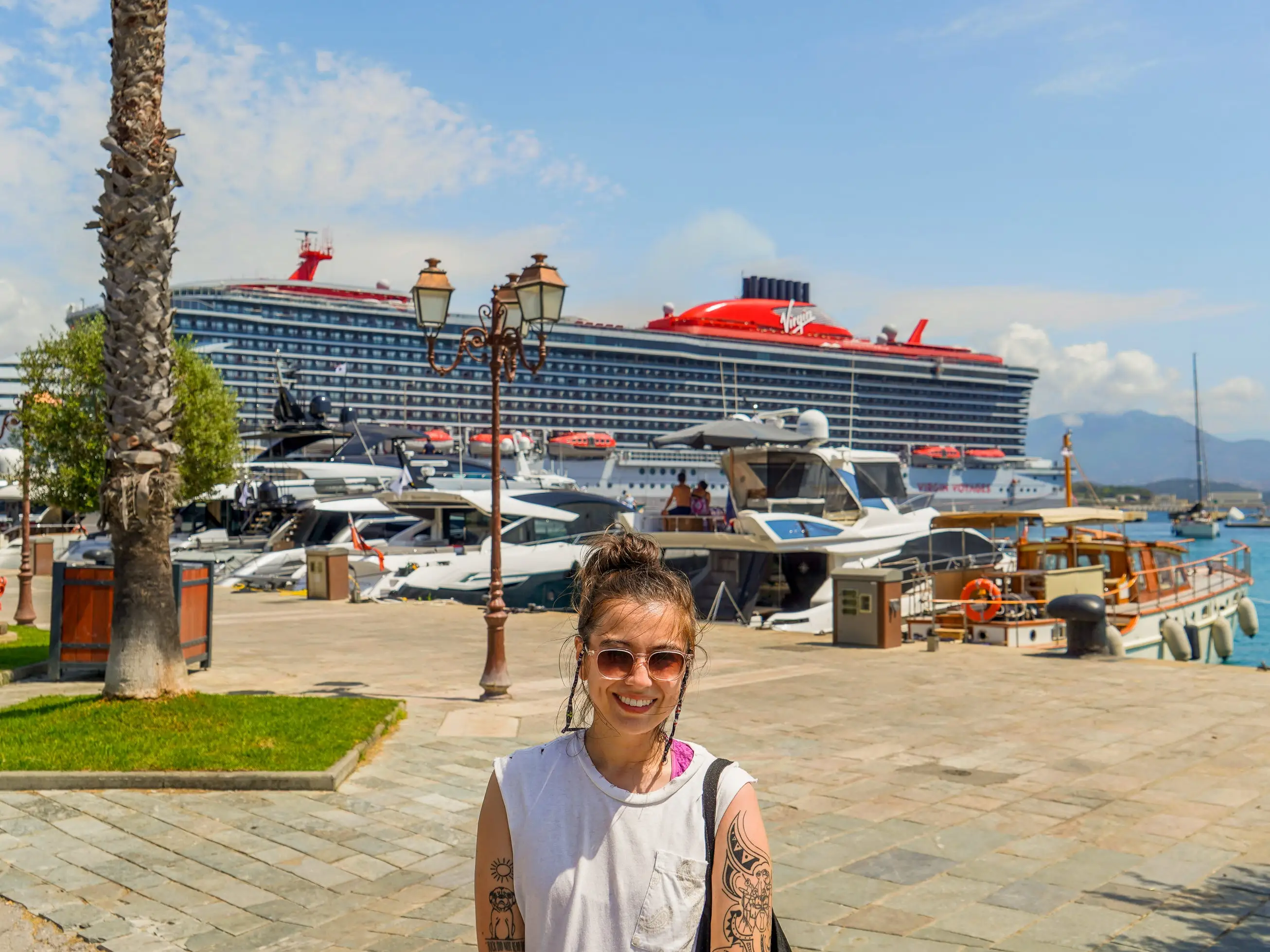 Th author stands smiling in front of a docked cruise ship and smaller vessels
