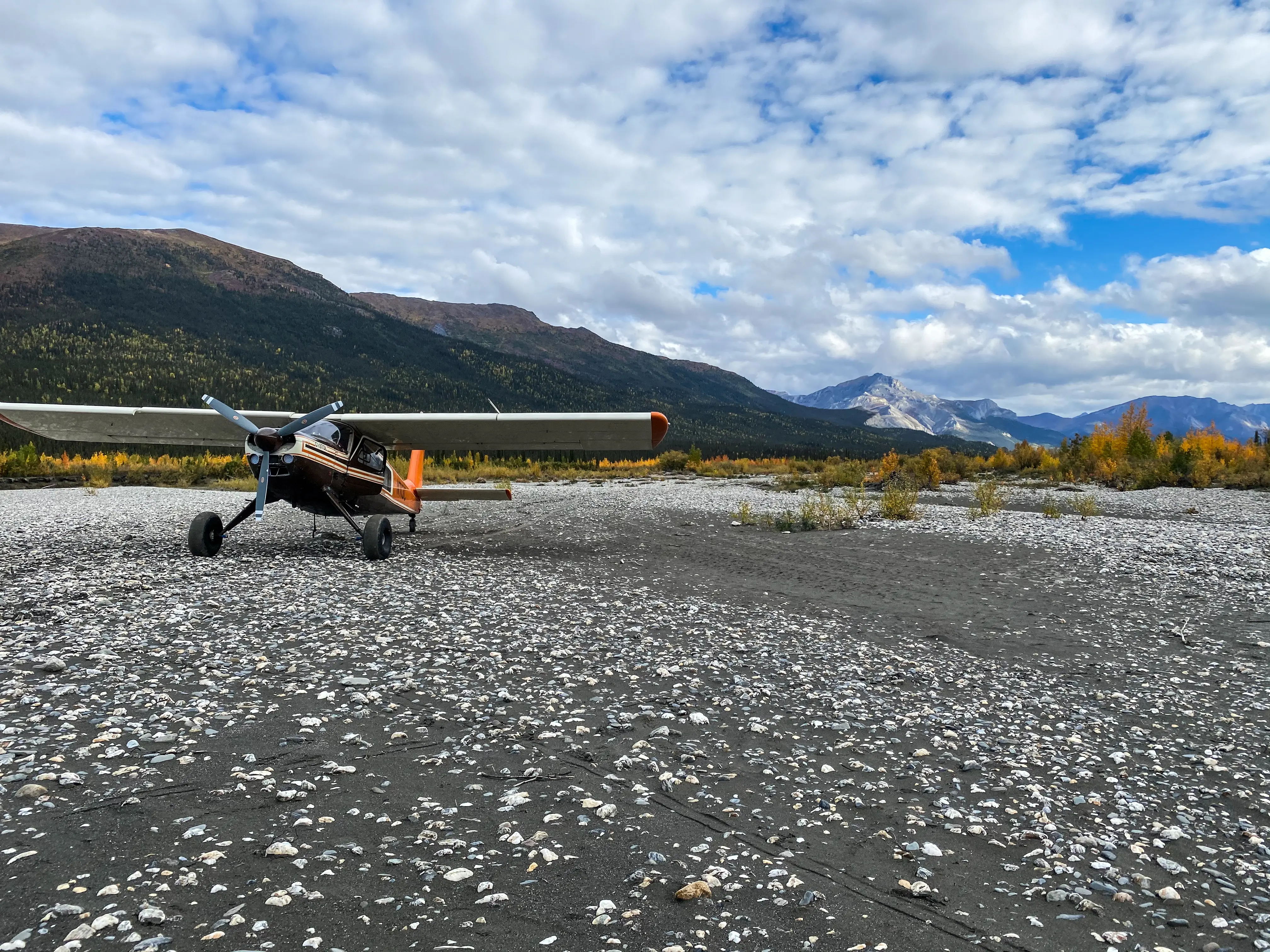 Bush Plane on rocky tarmac in front of mountains
