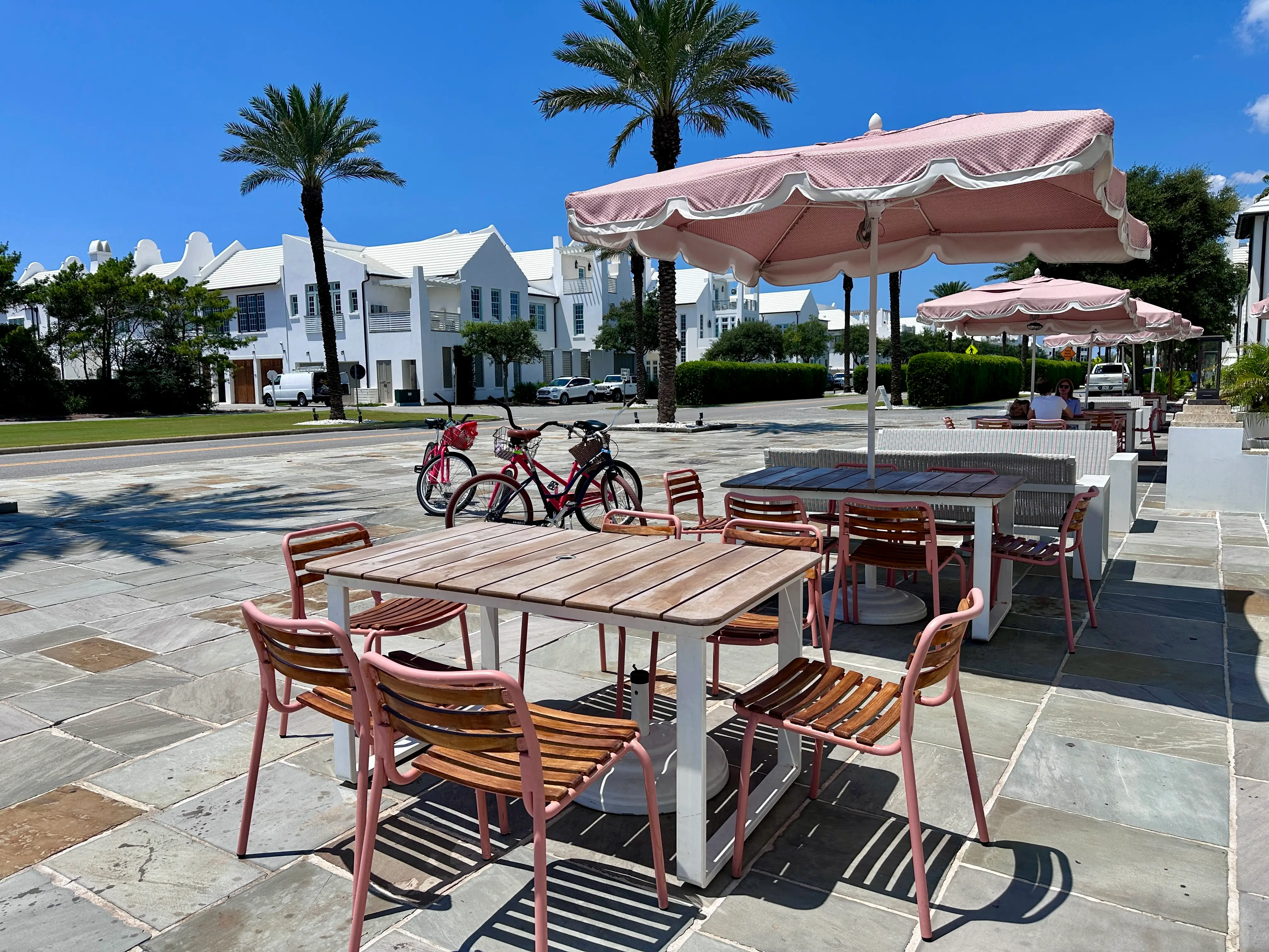 Pink umbrellas over outdoor seating on patio in Alys Beach