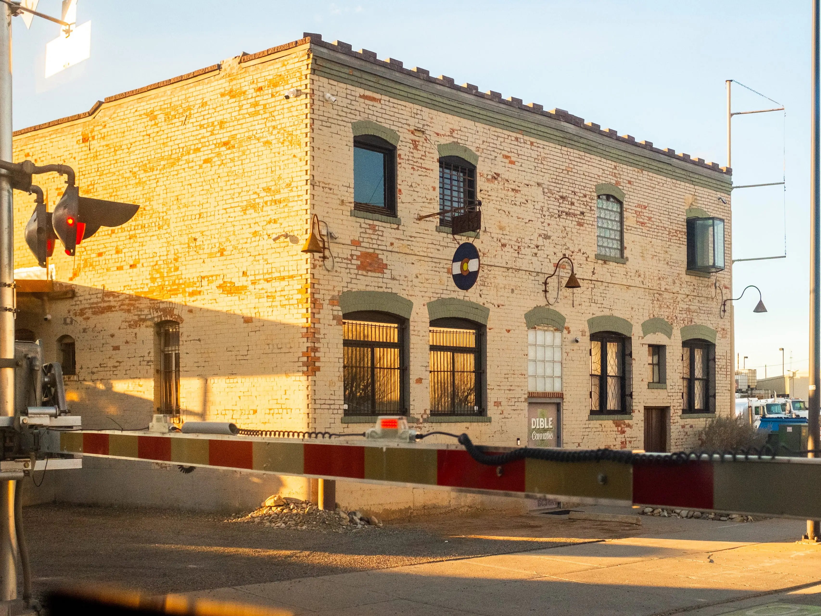 A view out the window of a train shows a brick building on the right and a train traffic light on the left.