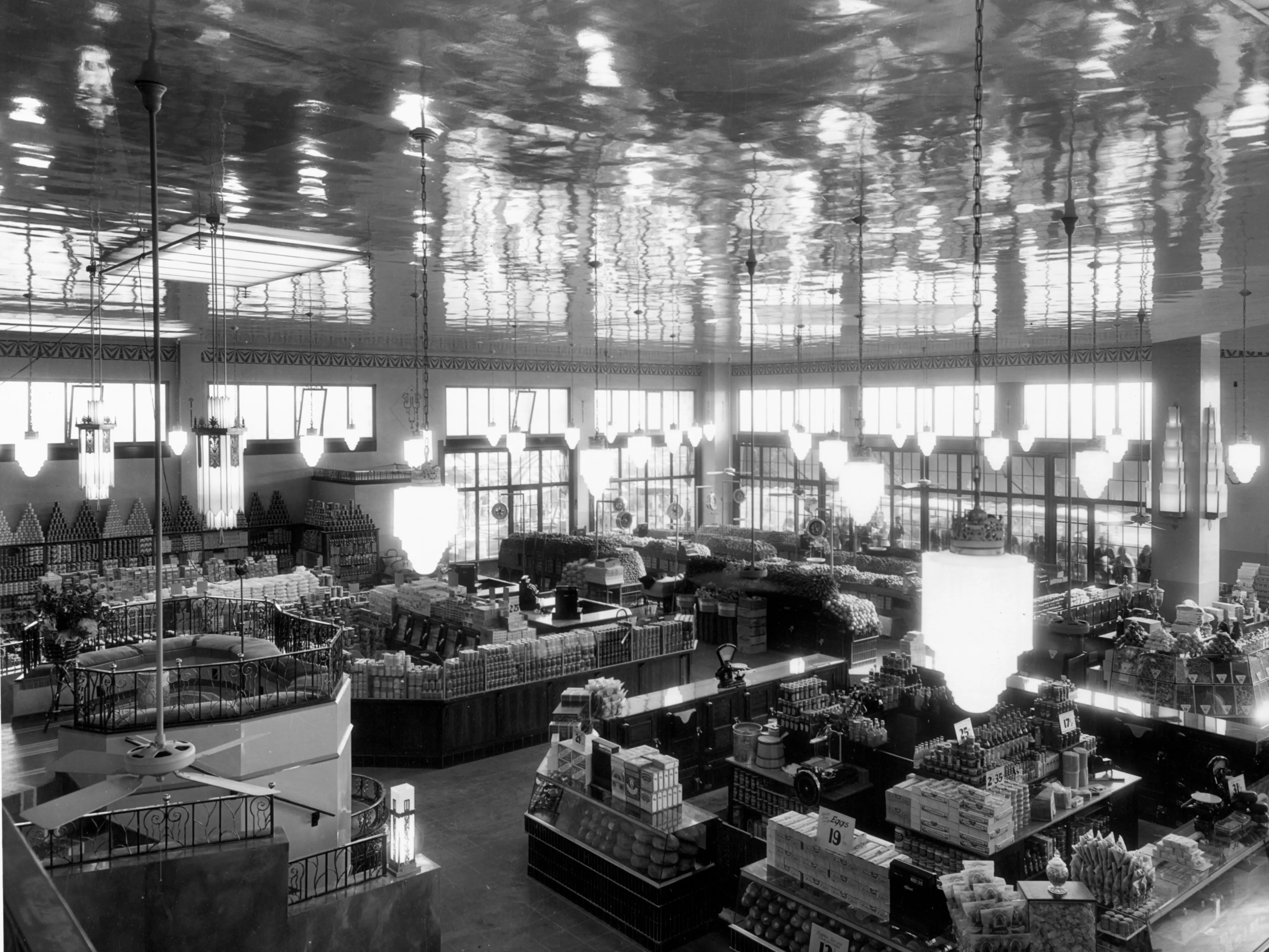 A grocery store with large windows and high ceilings with food stacked on shelves
