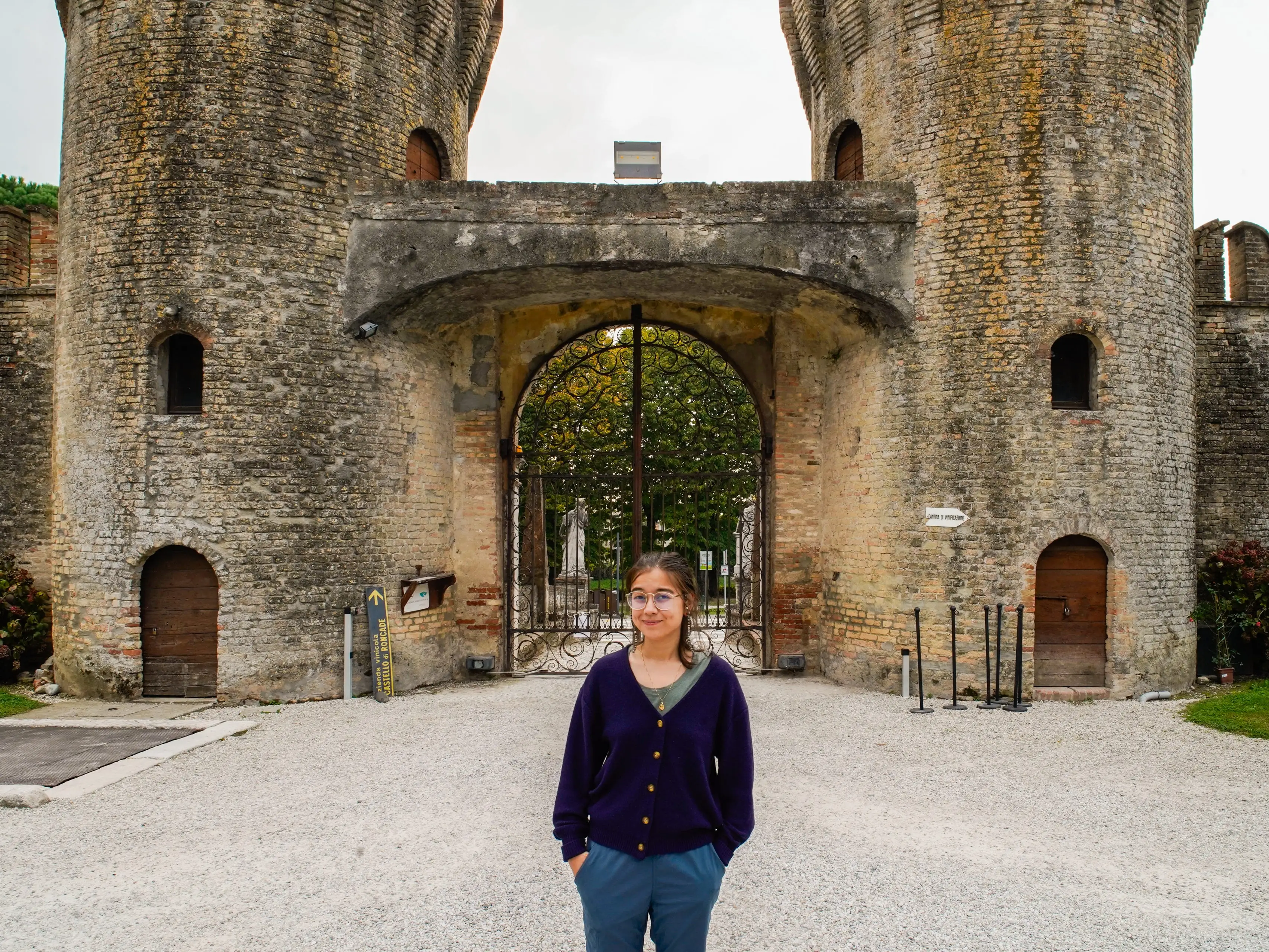 The author stands in front of a castle in Italy on a cloudy day