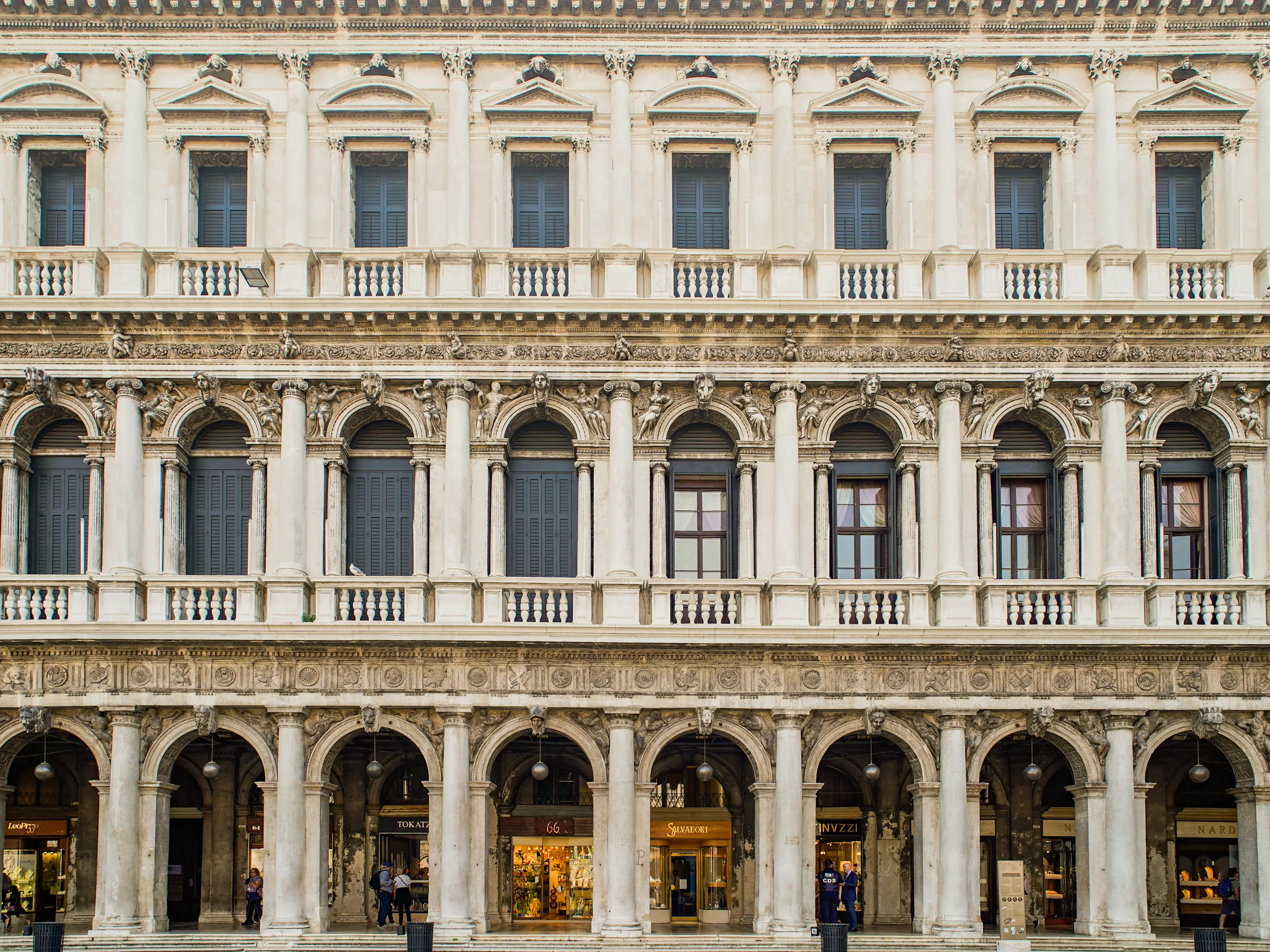 A white, three-story old-world building with pillars in Venice, Italy