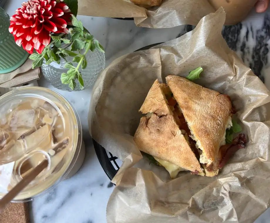 A breakfast sandwich and coffee on a table.