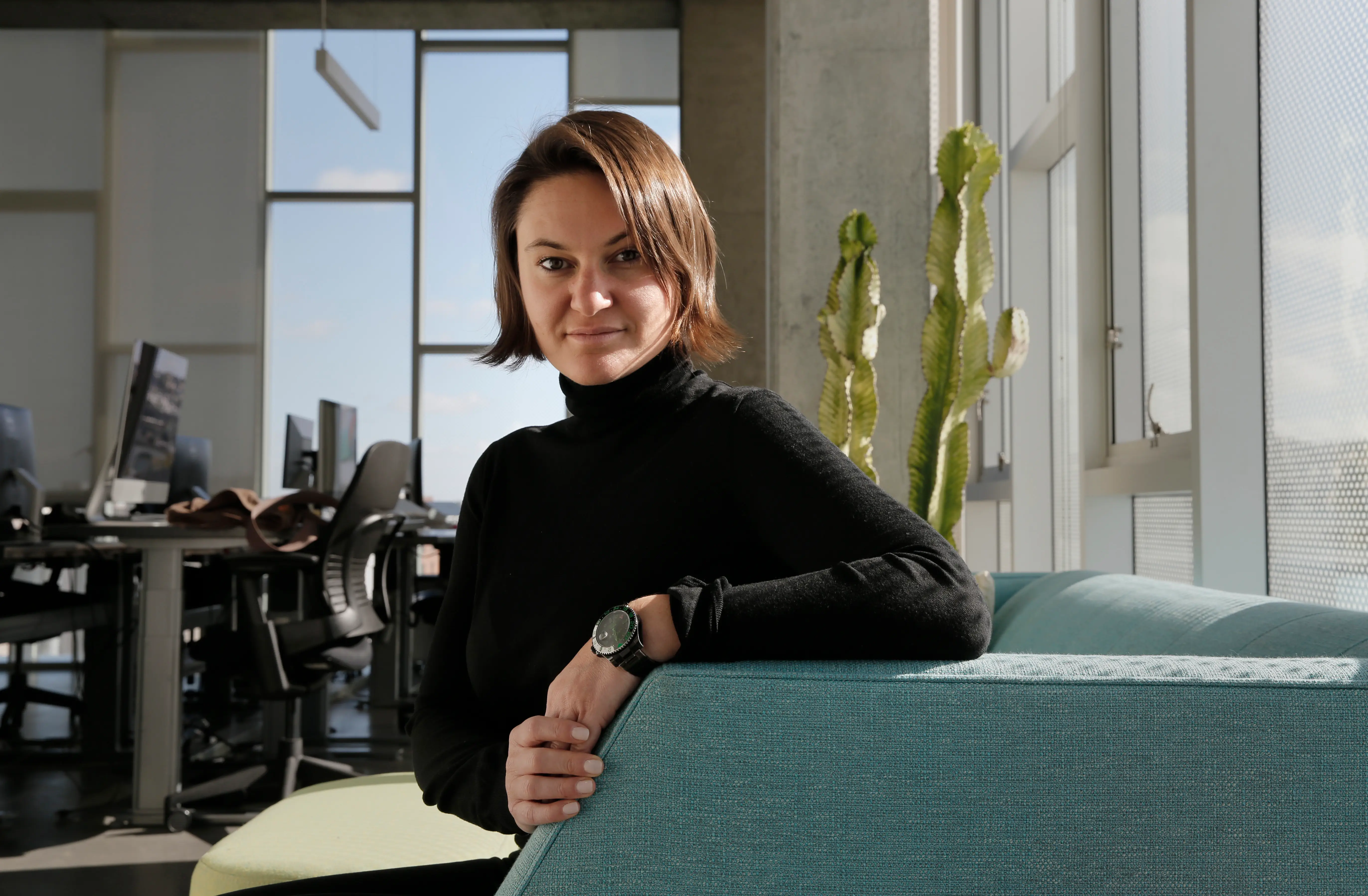 Eugenia Kuyda in a black turtleneck, sitting on a green couch.