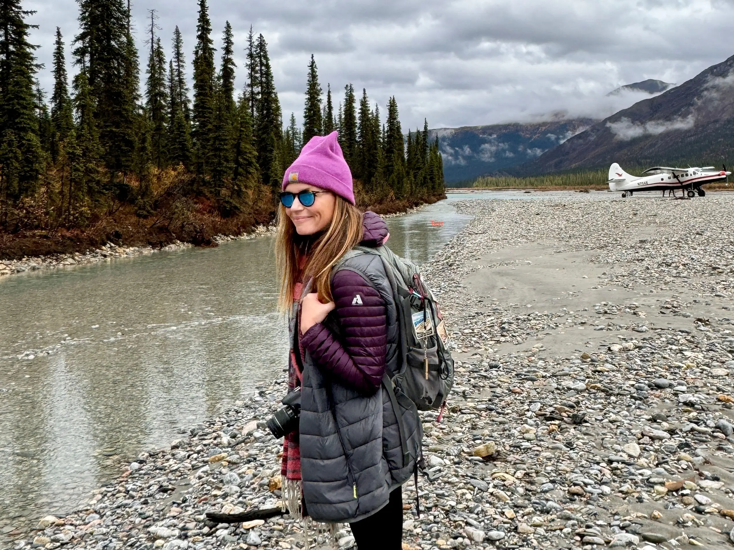 Emily standing on rocks with a backpack on.