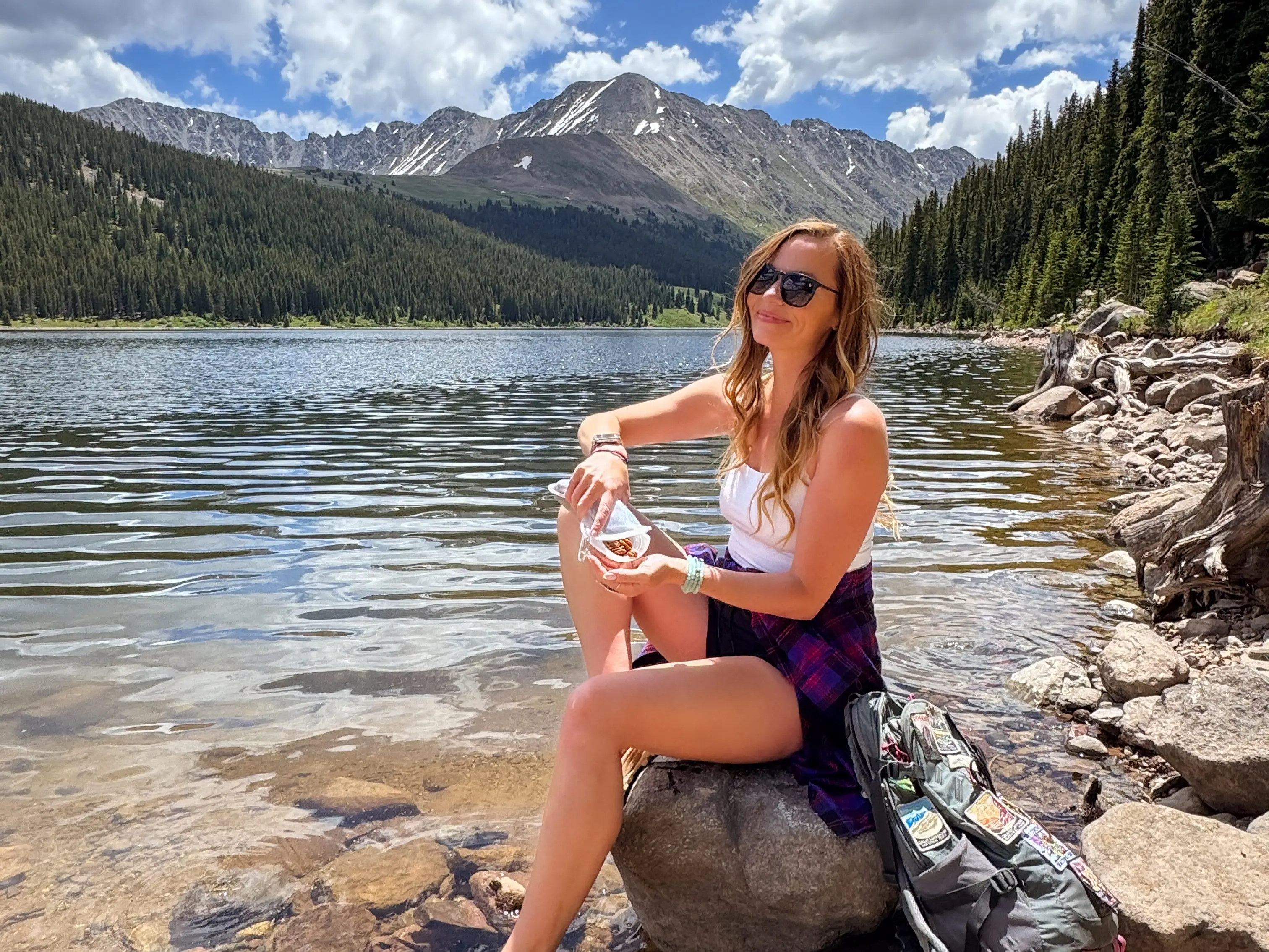 Emily sitting on a rock eating a snack.