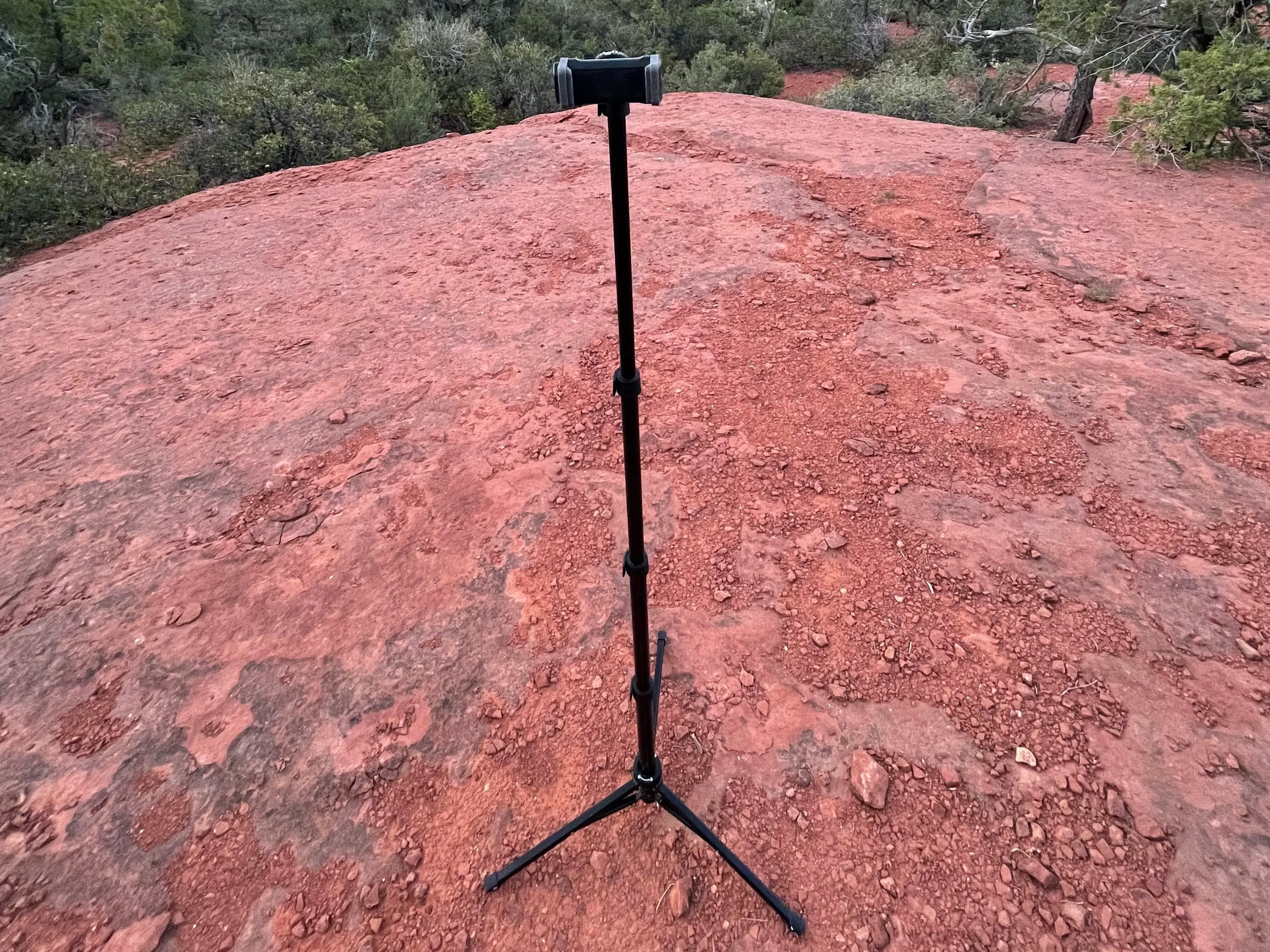 A standing tripod on red, sandy ground.