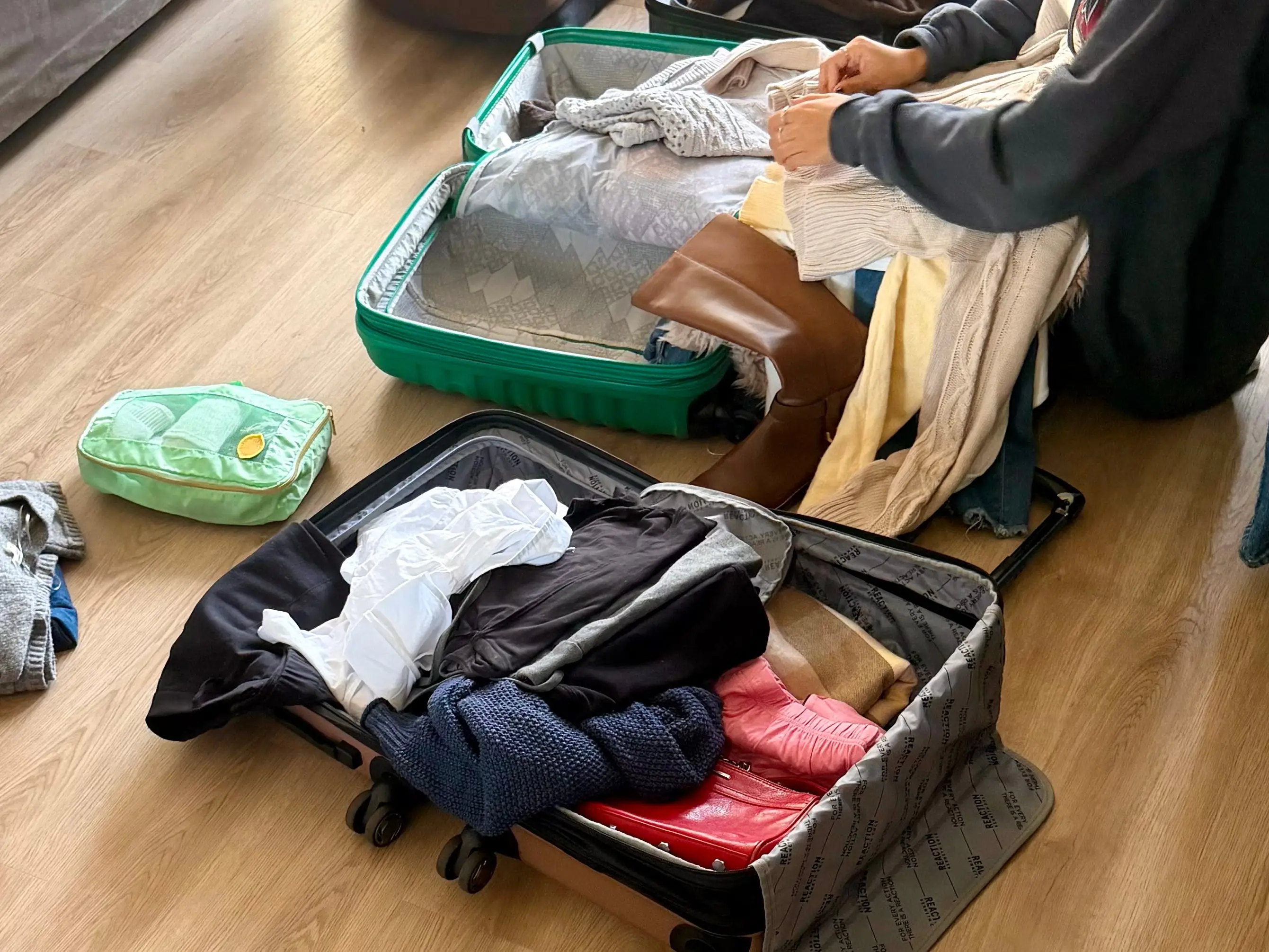 Open suitcases and clothes strewn about on a floor.