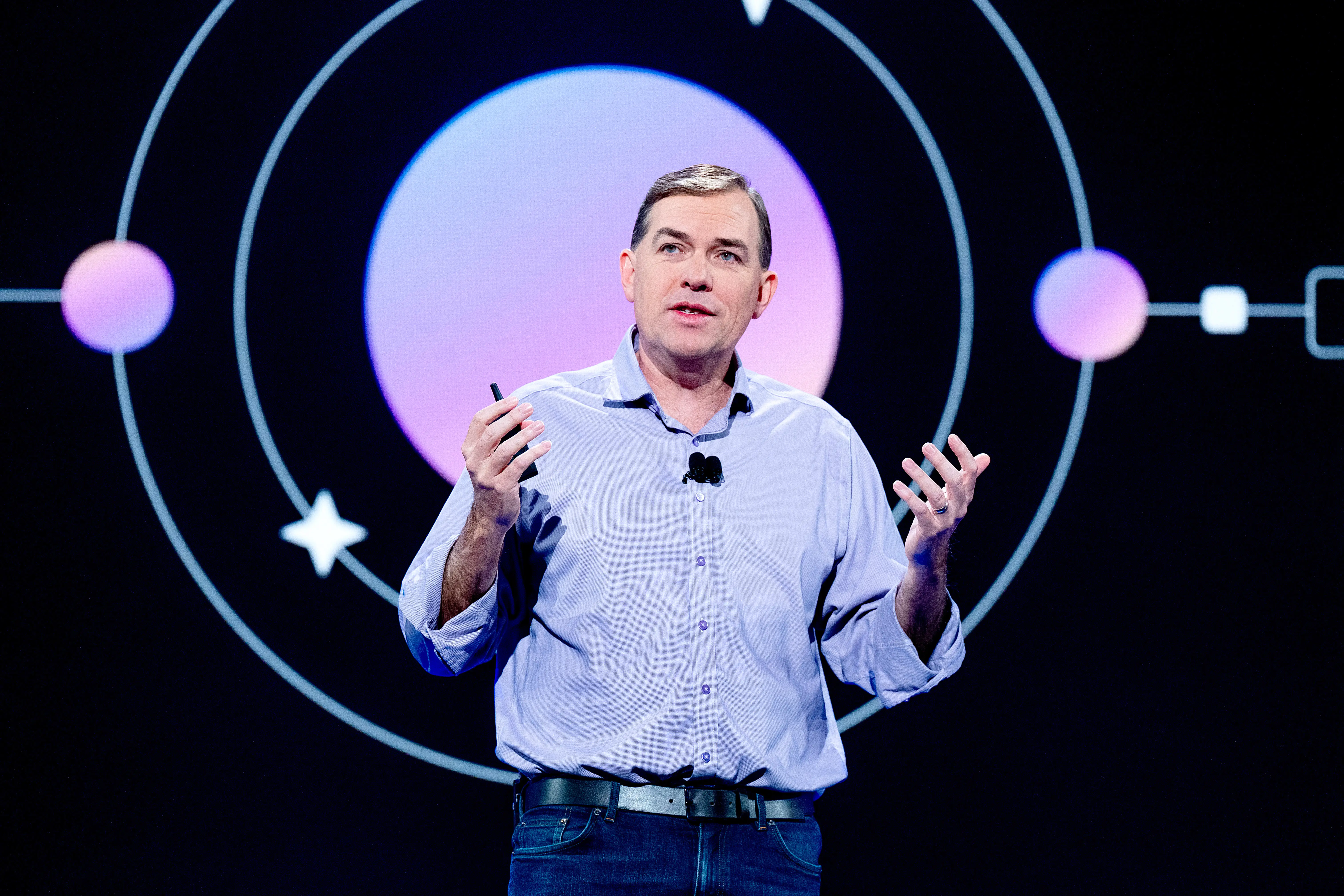 Amazon Web Services CEO Matt Garman, standing onstage at CES, wearing a light purple shirt and gesturing with his hands.