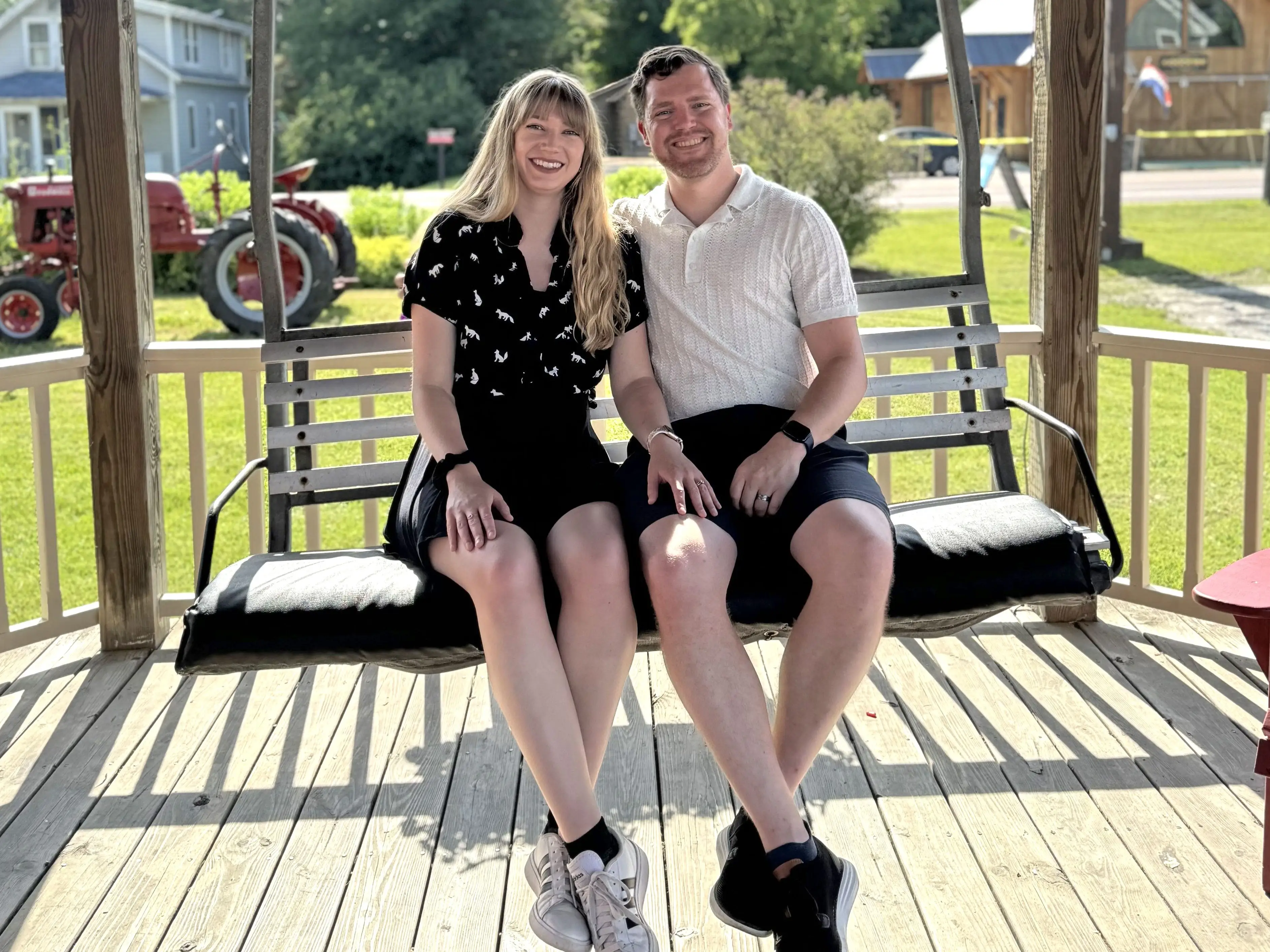 Emily and her husband sit on a bench swing.