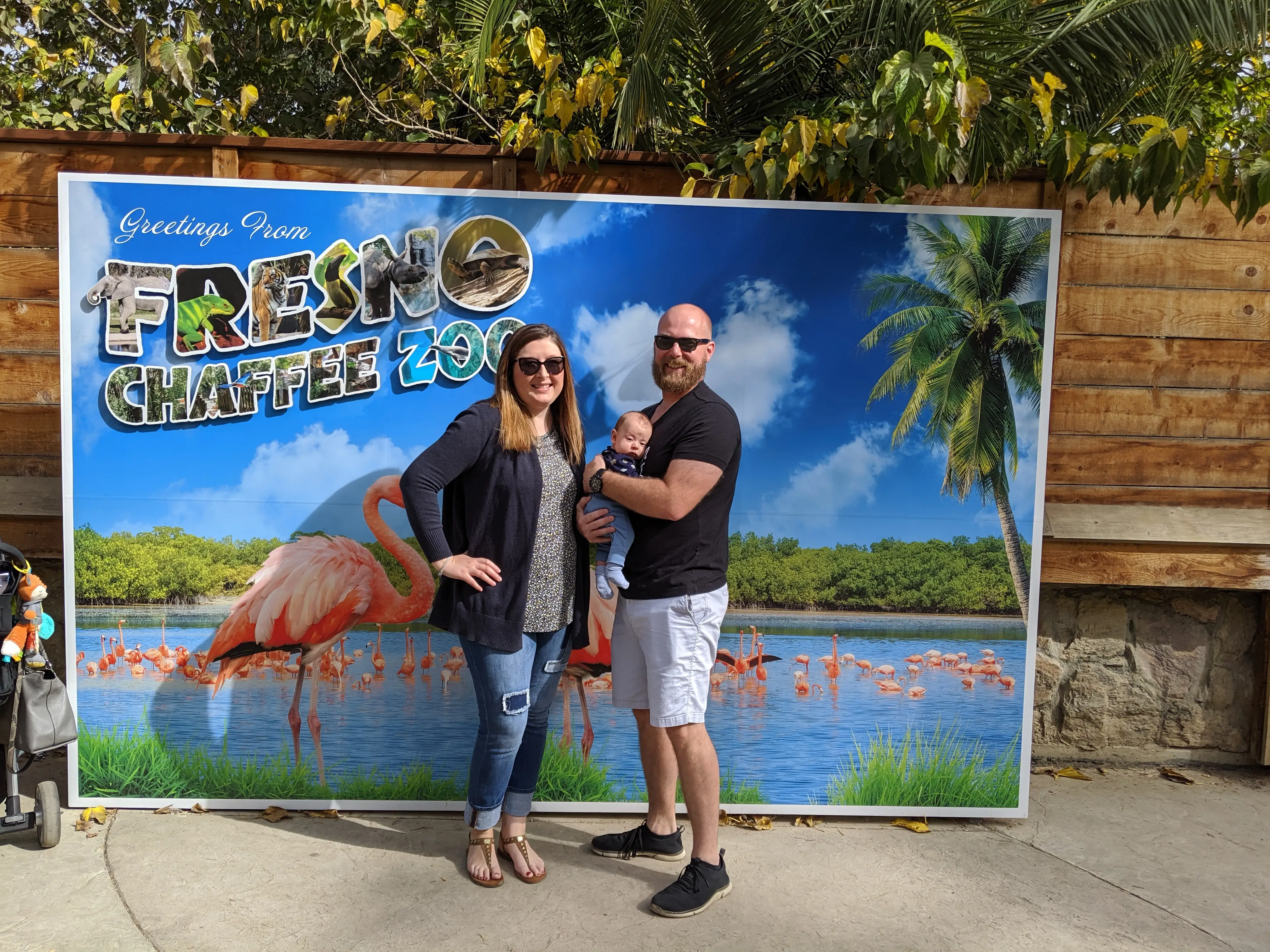 Couple posing in front of Fresno zoo sign with baby