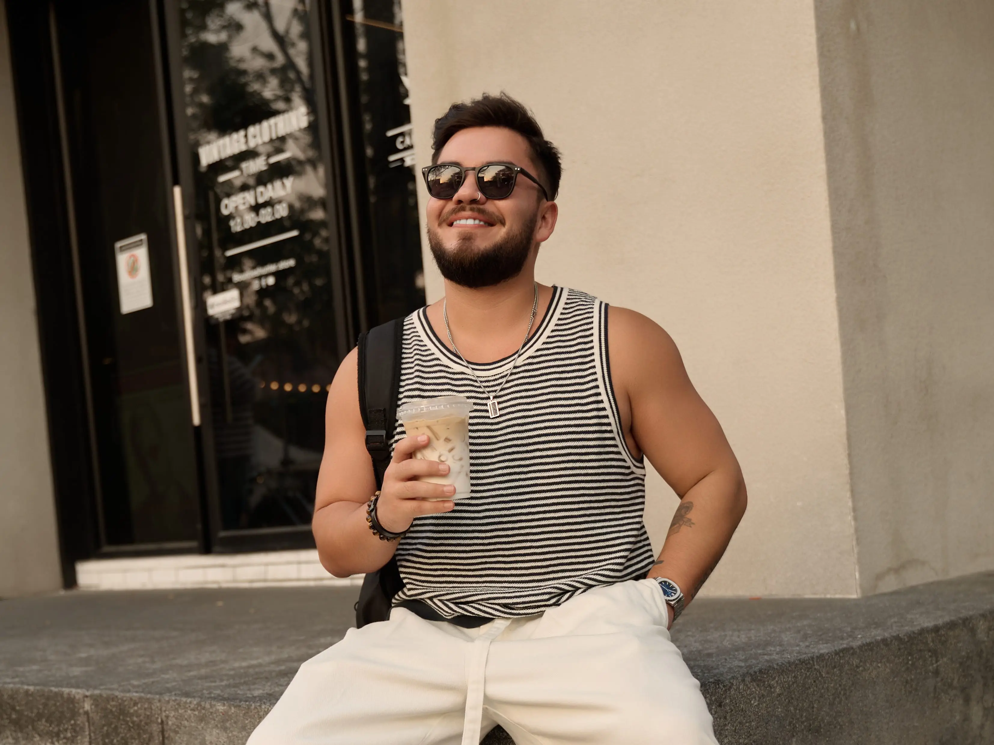 A man posing with a coffee in the streets of Bangkok.