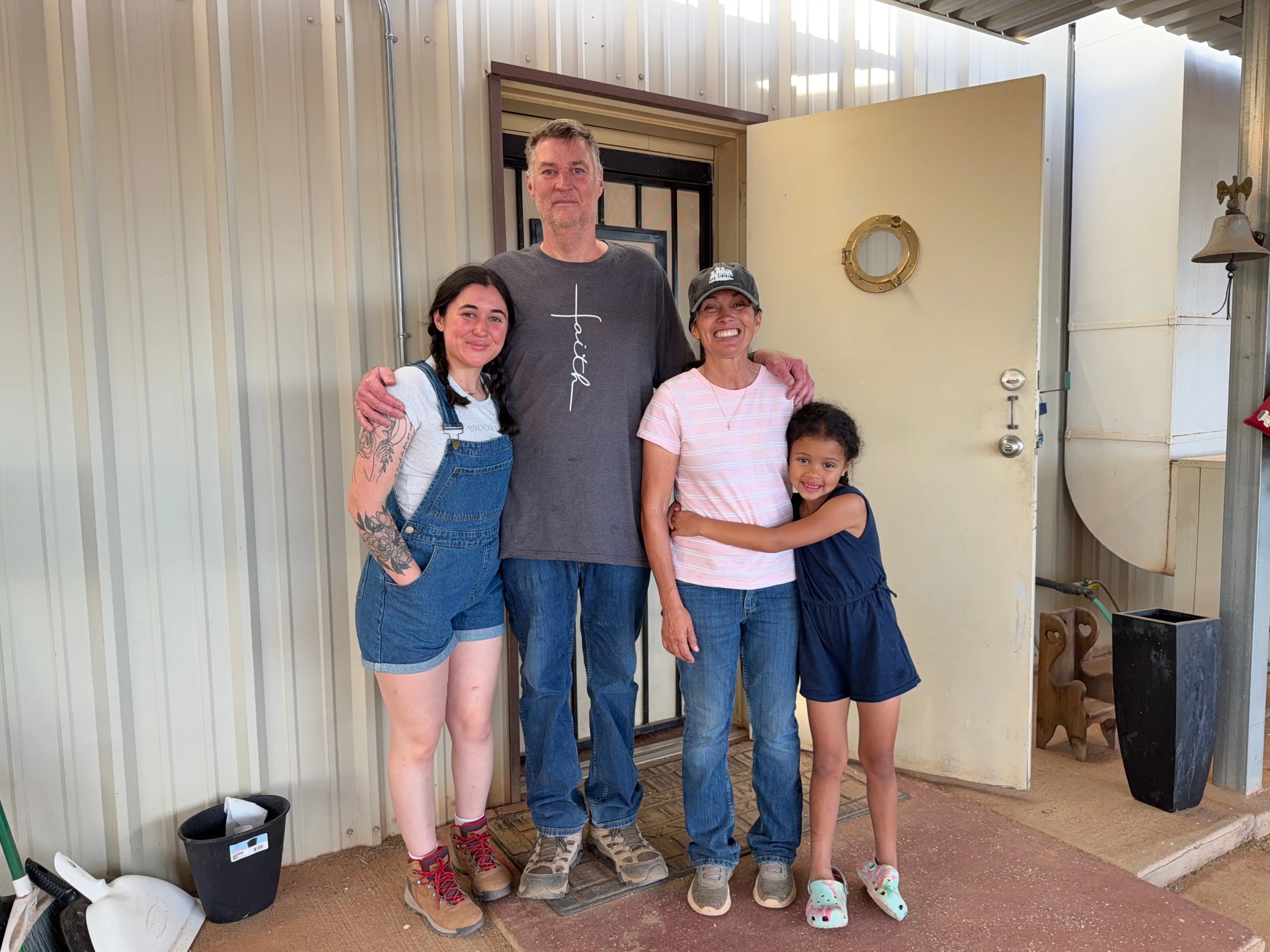 A family stands in front of the doorway to a garage apartment.