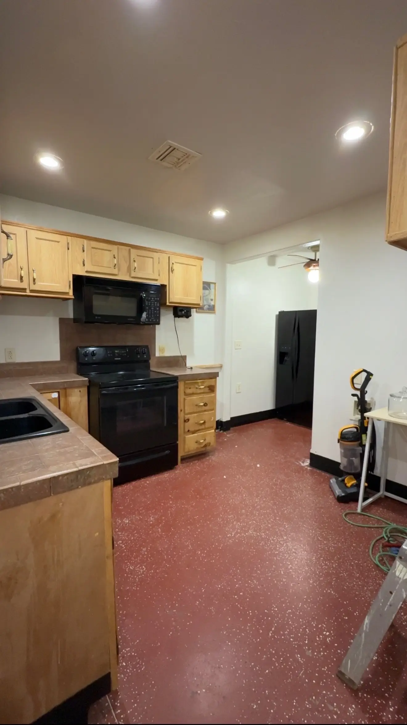 A kitcehn with red floors and wood cabinetry.