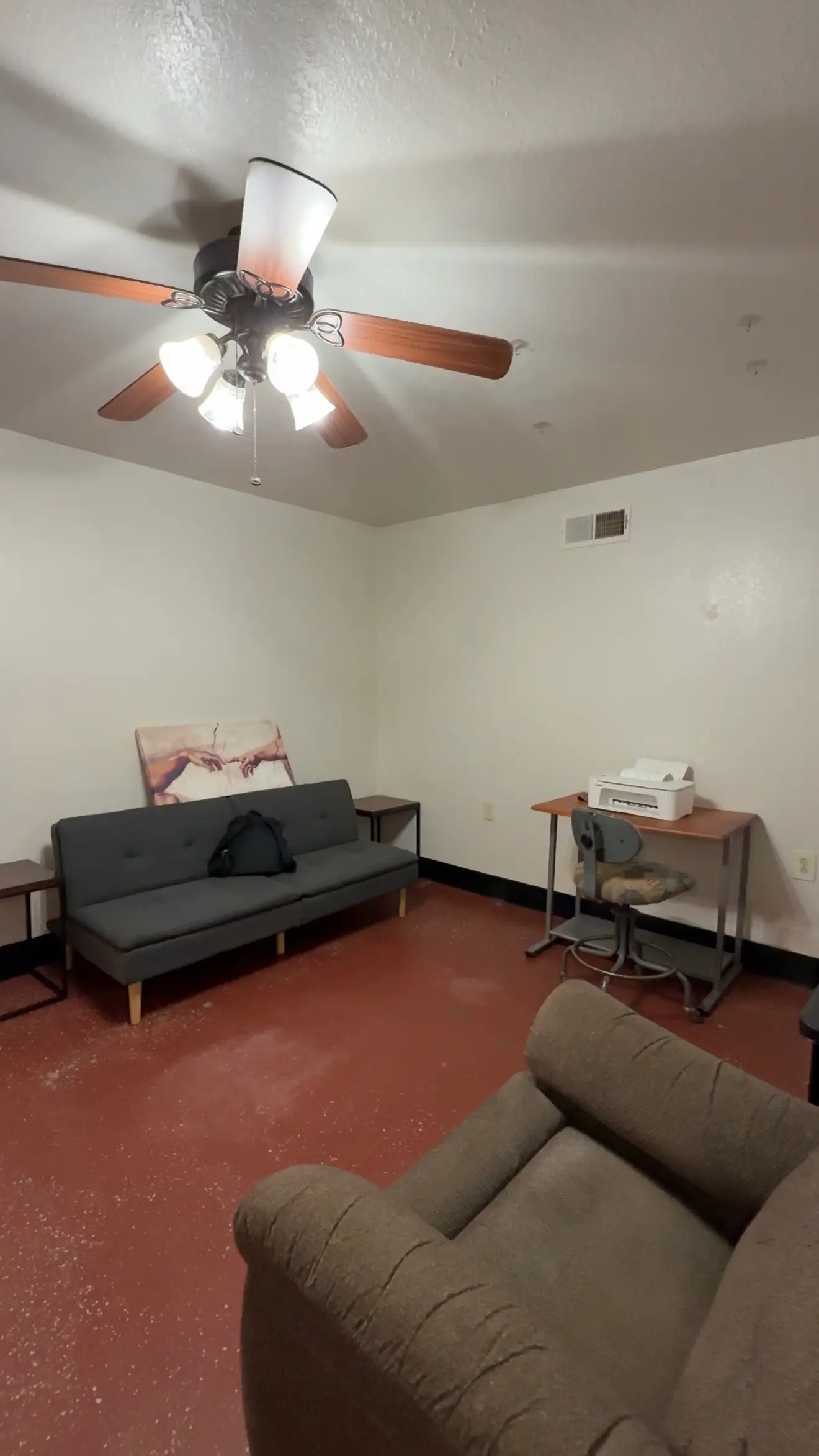 A living room with a couch, a small desk, and a chair.