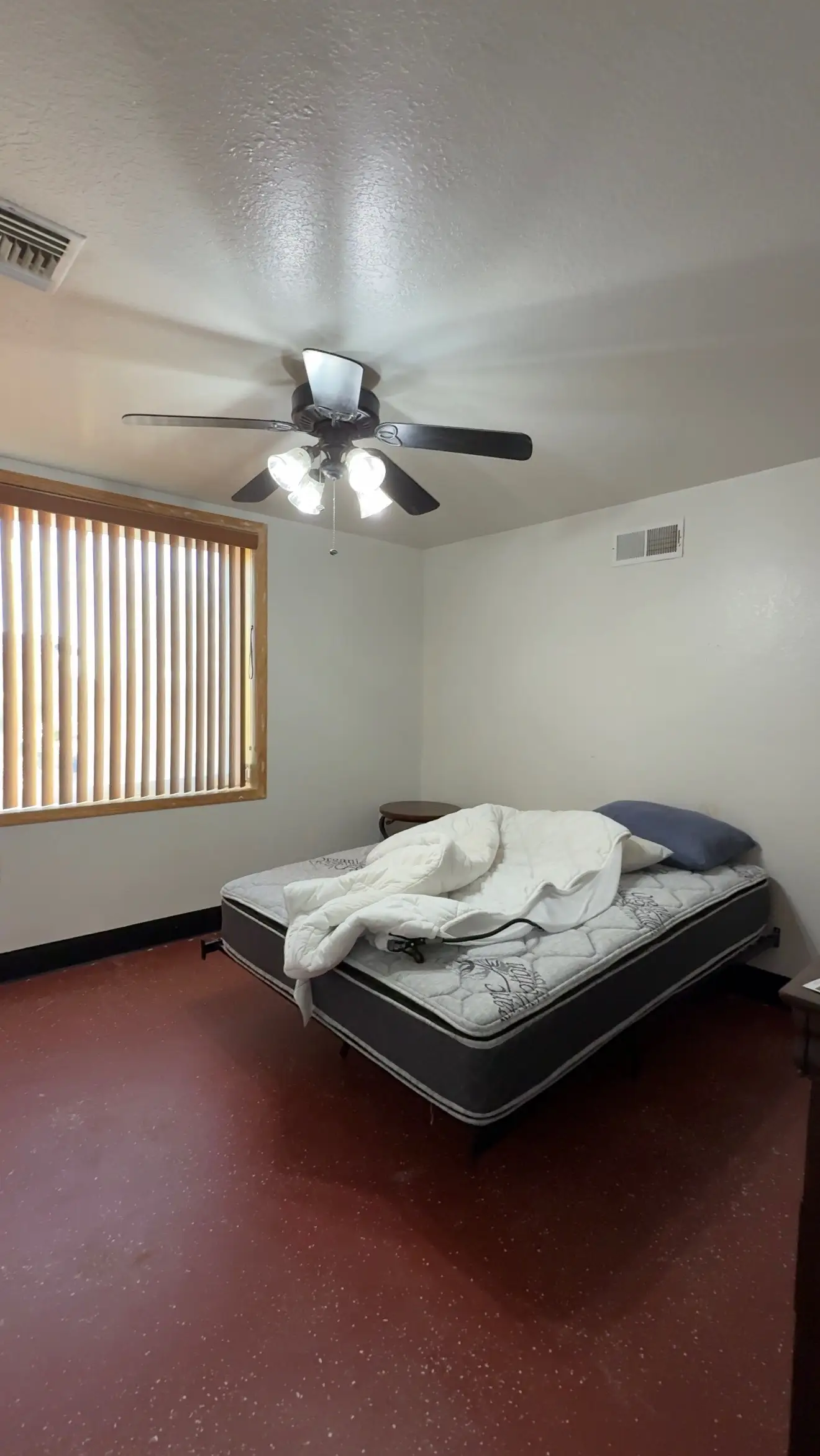 A bedroom with a mattress and a wooden window.