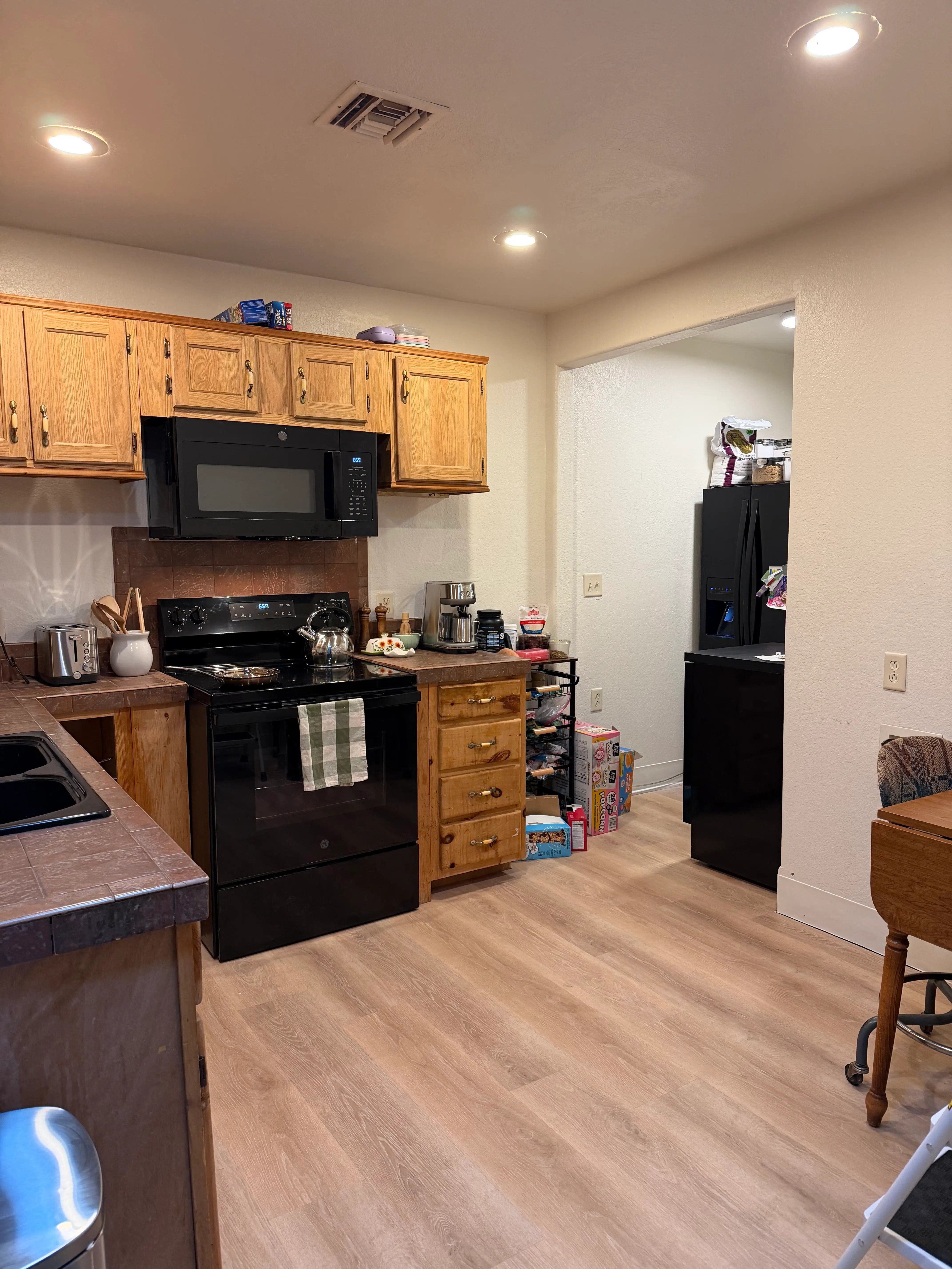 A kitchen with wooden floors, wood cabinetry, and a small table.