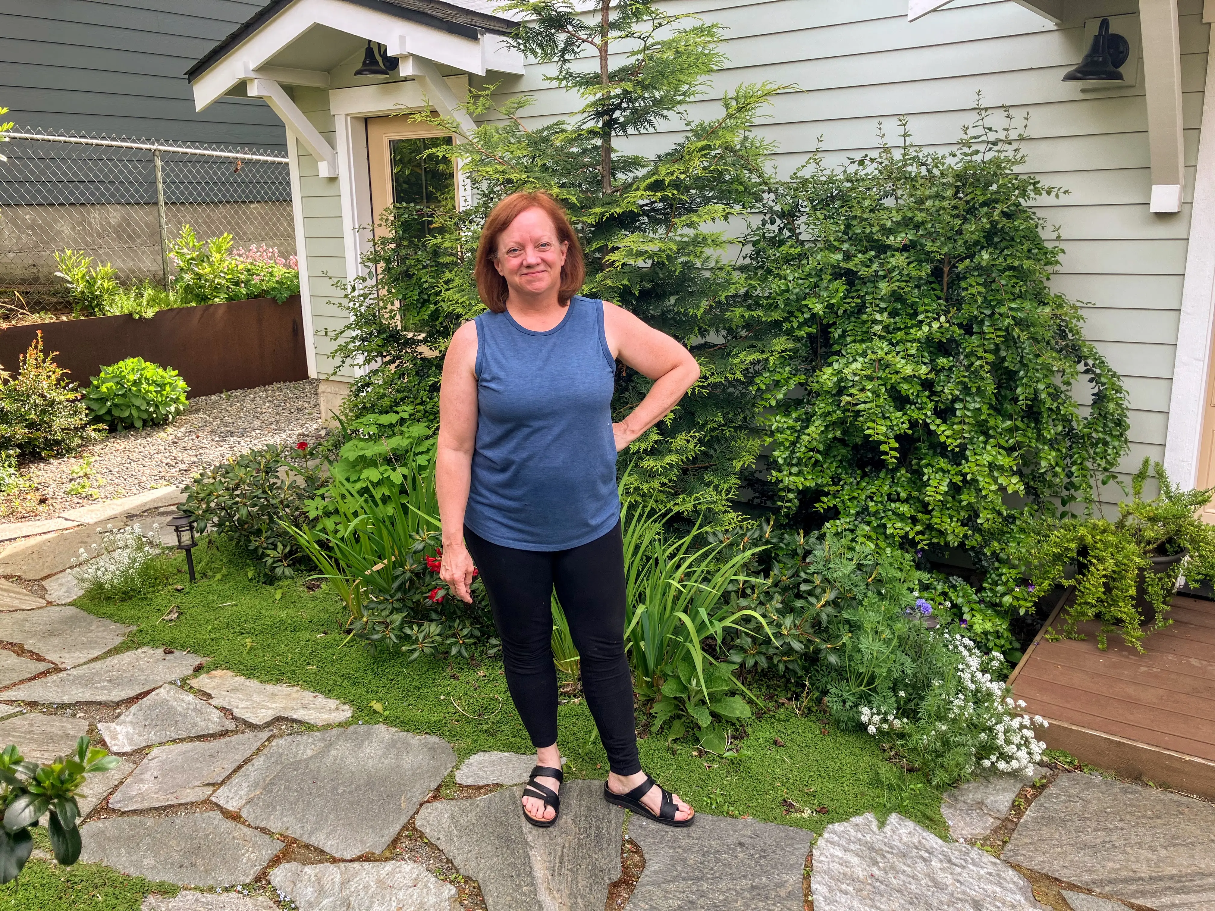 Woman standing in front of plants next to home