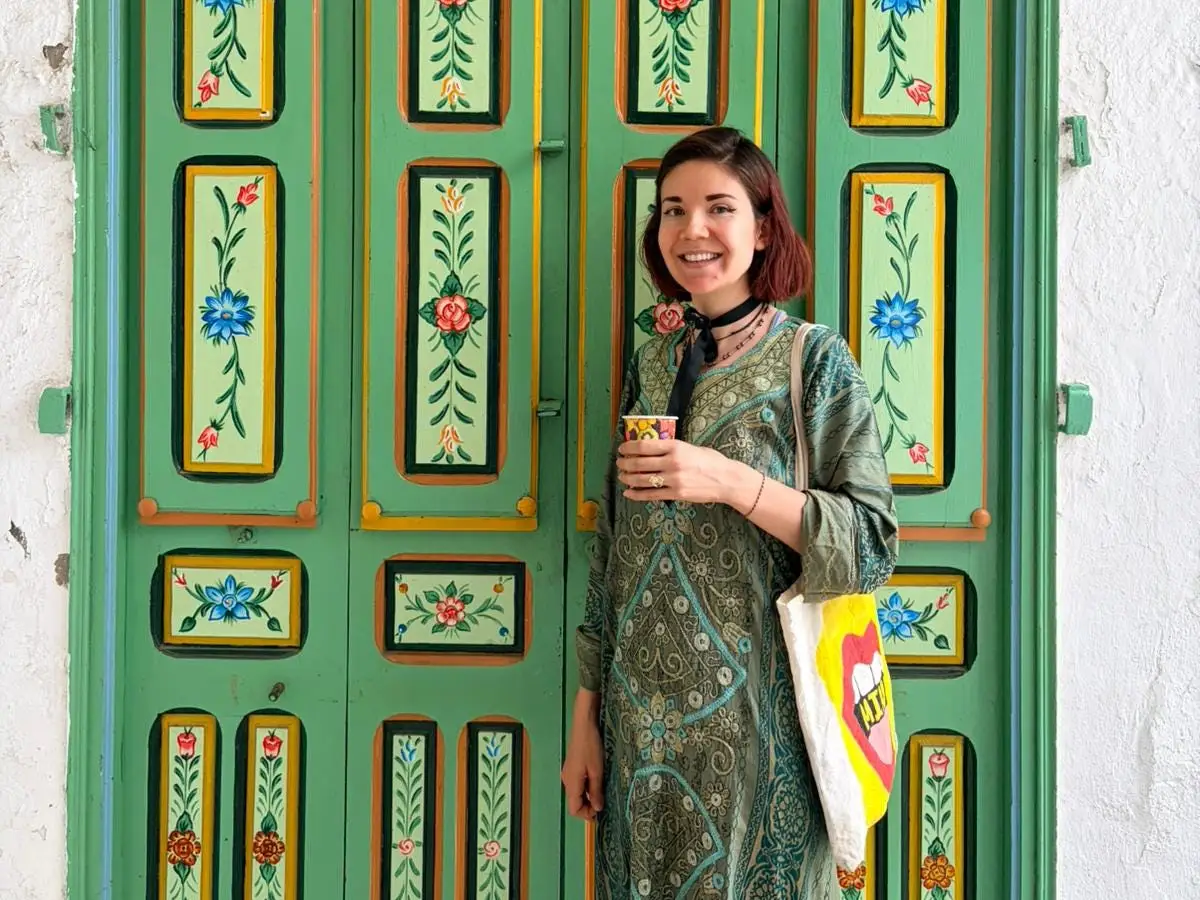 The author poses in front of a colorful piece of furniture.