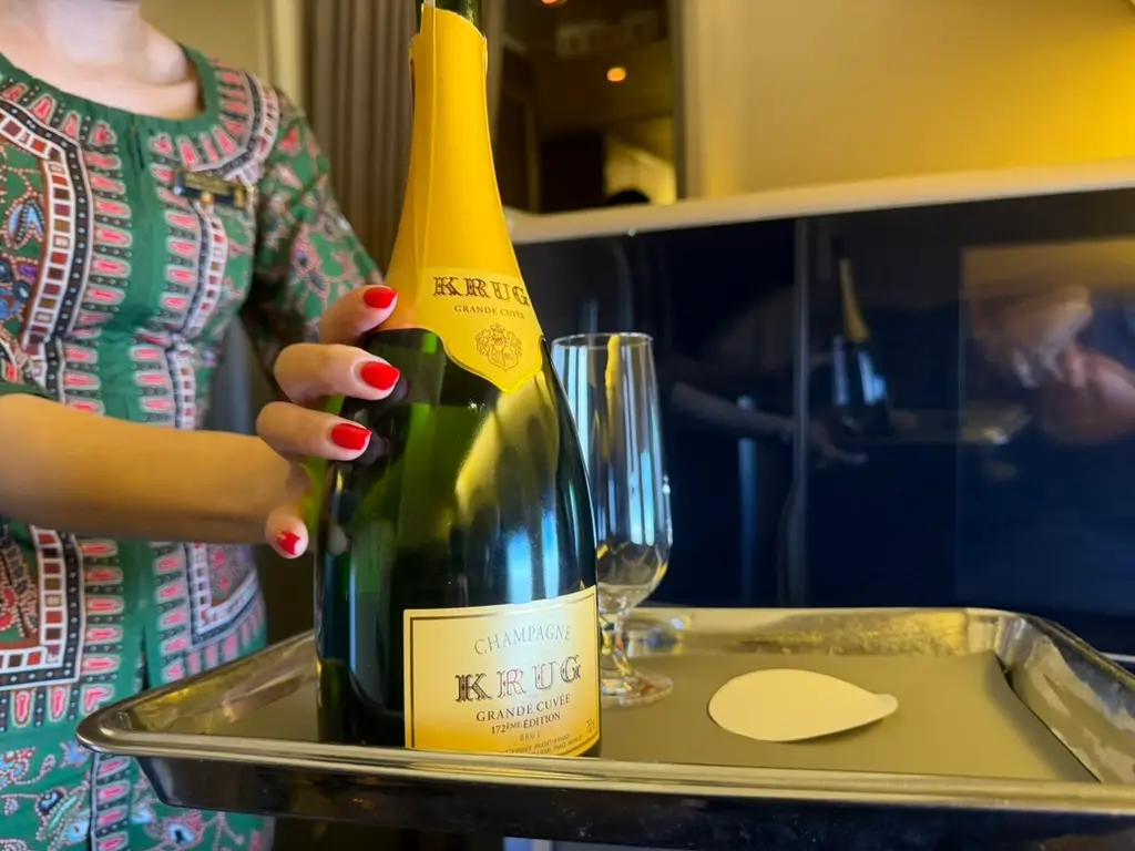 Hand on bottle of Champagne on metal tray