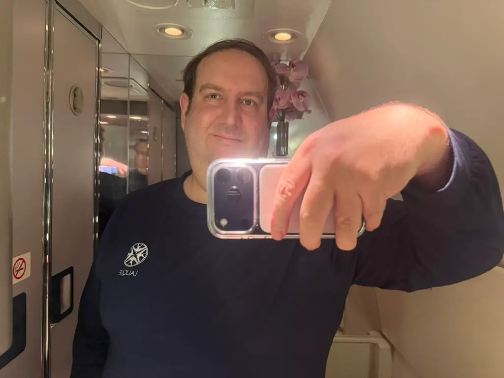 Man taking selfie in bathroom mirror on Singapore Airlines flight
