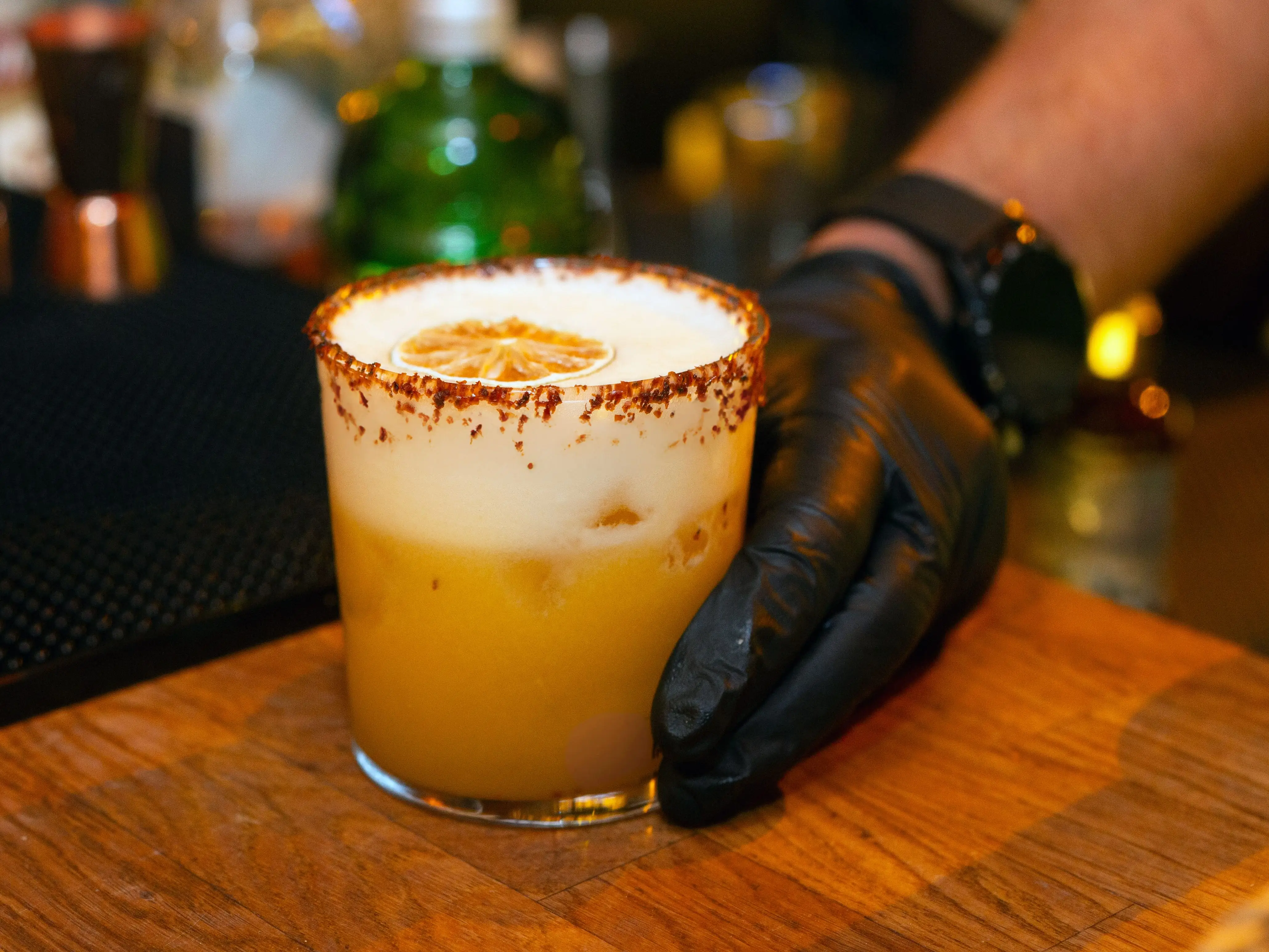 A bartender puts a passionfruit margarita on a bar.