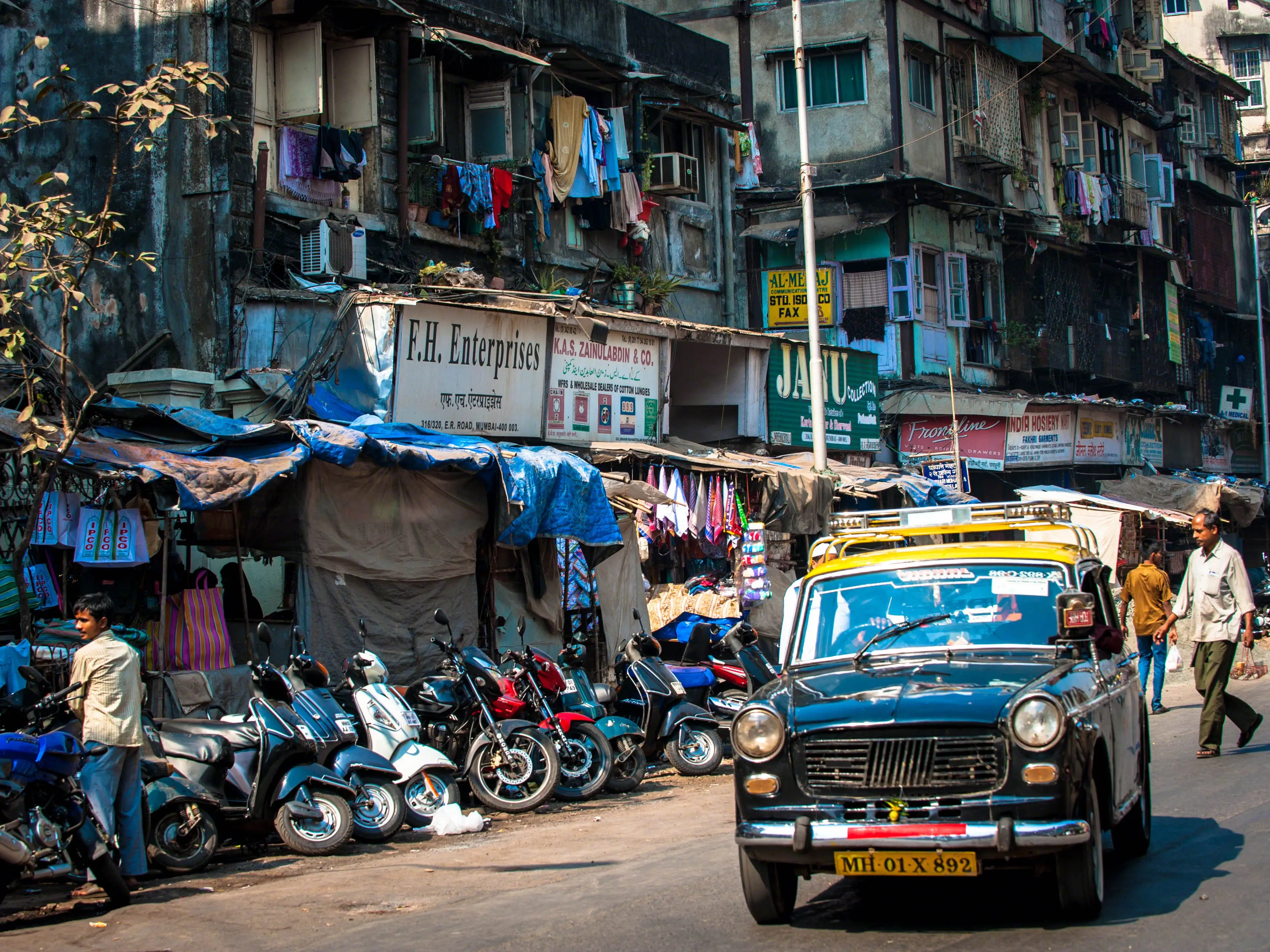 Car next to line of motorcycles against buildings in Mumbai