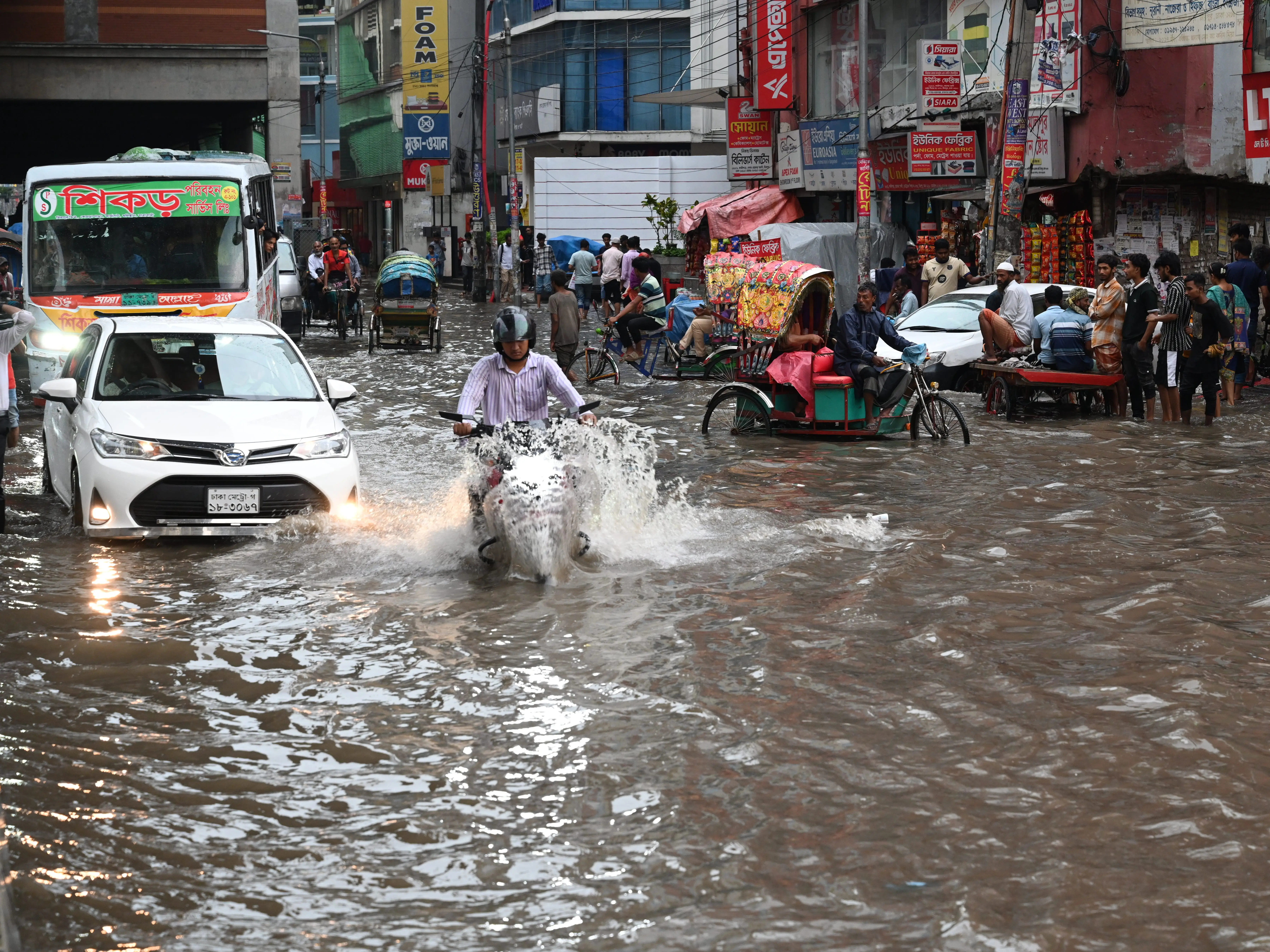 A man drives a motorcycle through deep floodwater in Dhaka, Bangladesh.