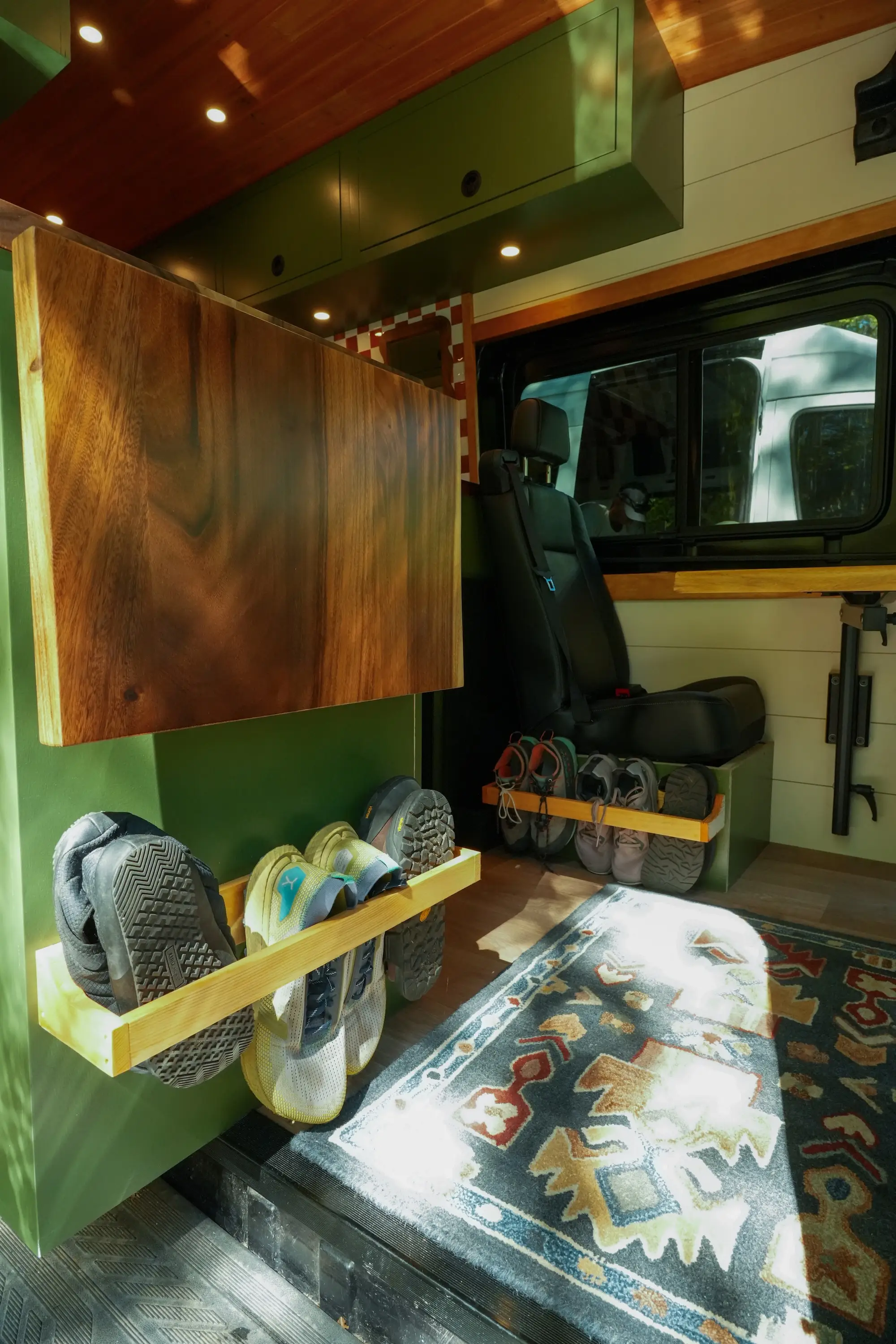 A van with built-in shoe storage and wooden and green cabinetry.