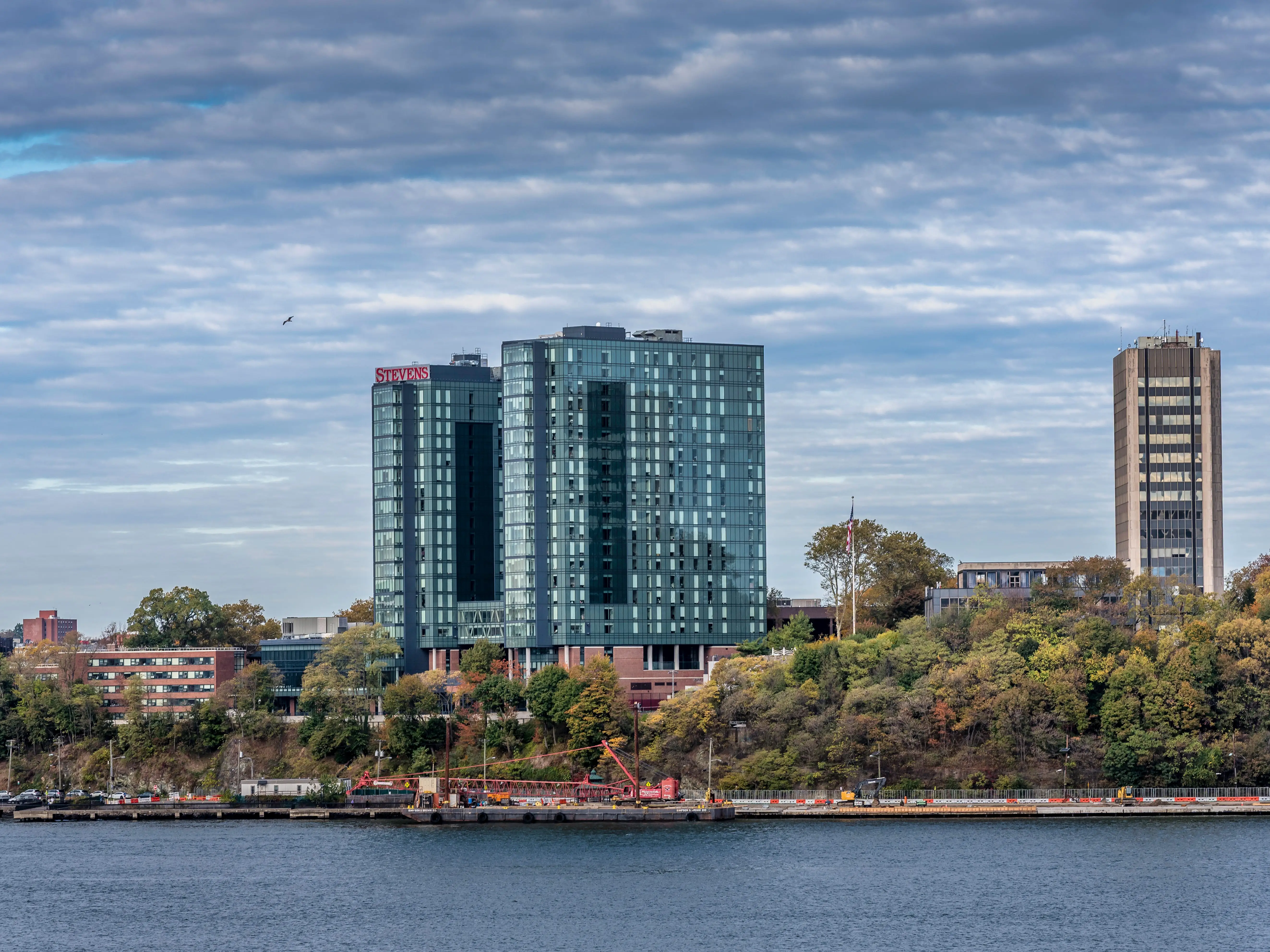 NYC NY USA October 26 2025: The campus of Stevens Institute of Technology can be seen directly across the Hudson River at Little Island. The rather small campus for the most part sits on a bluff in Hoboken overlooking the Hudson River. The administration building at right, built in 1961, is at the highest point on the campus, Castle Point, which is about 100 feet above the mean level of the river. The two larger buildings near the center are student dormitories, completed in 2022.