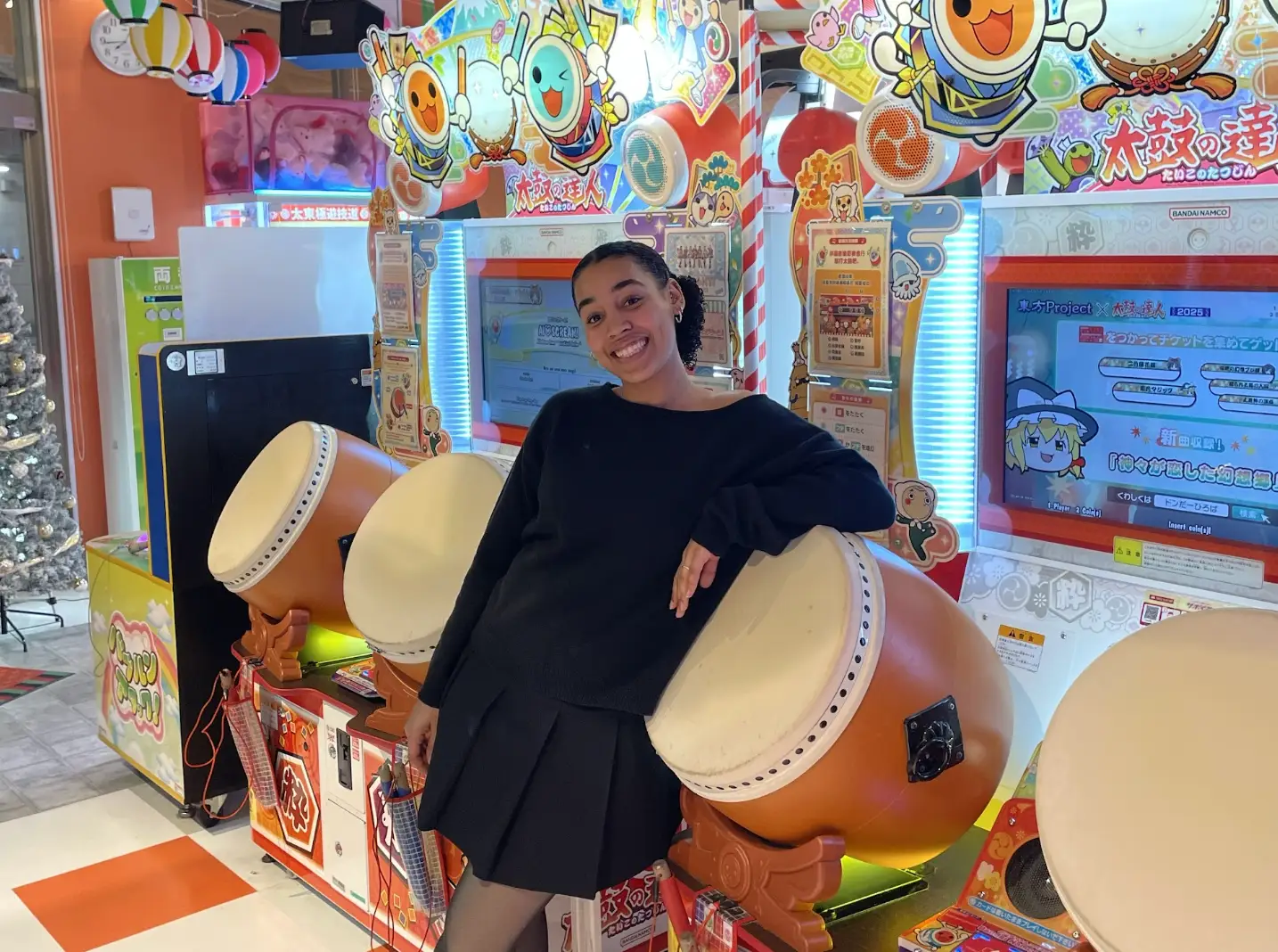 The writer wearing an all-black outfit and standing at an arcade in Tokyo.