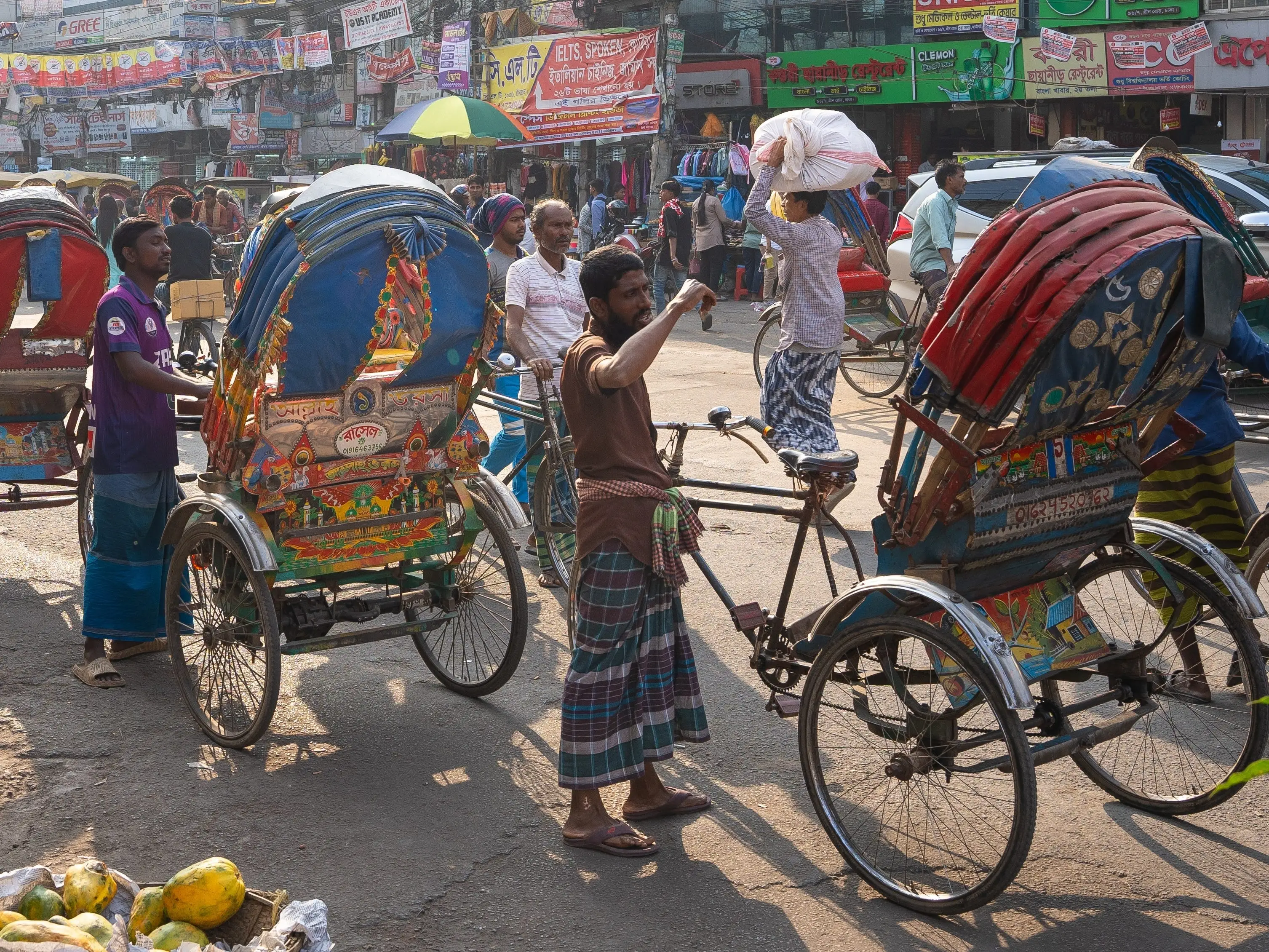 Drivers stand next to rickshaws in the streets of Dhaka.