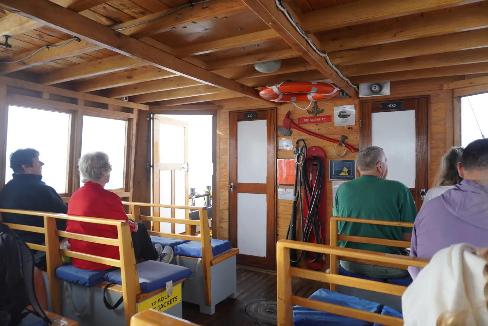 People sitting on wooden benches on an old ferry.