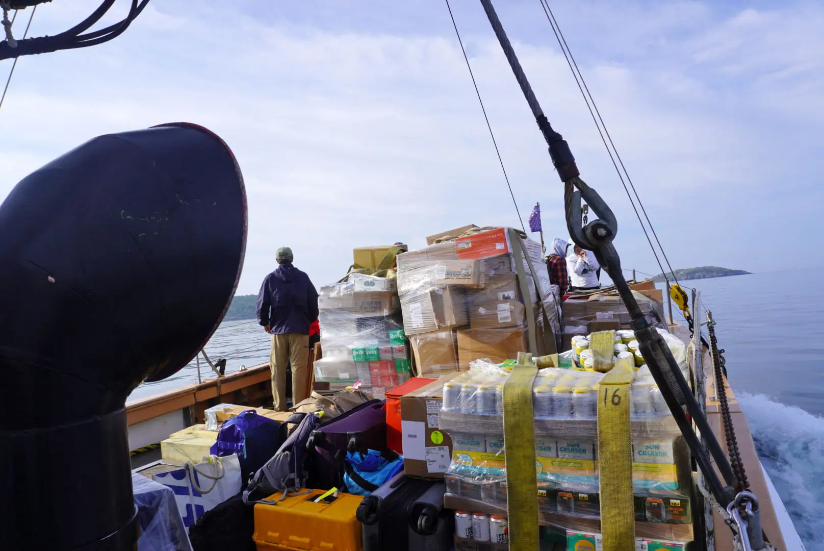Piles of boxes and drinks on the front of a boat.